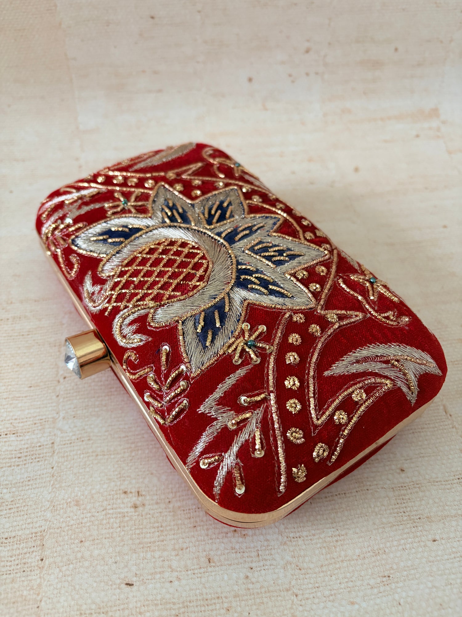 Decorative red pouch with gold and silver embroidery on a beige background