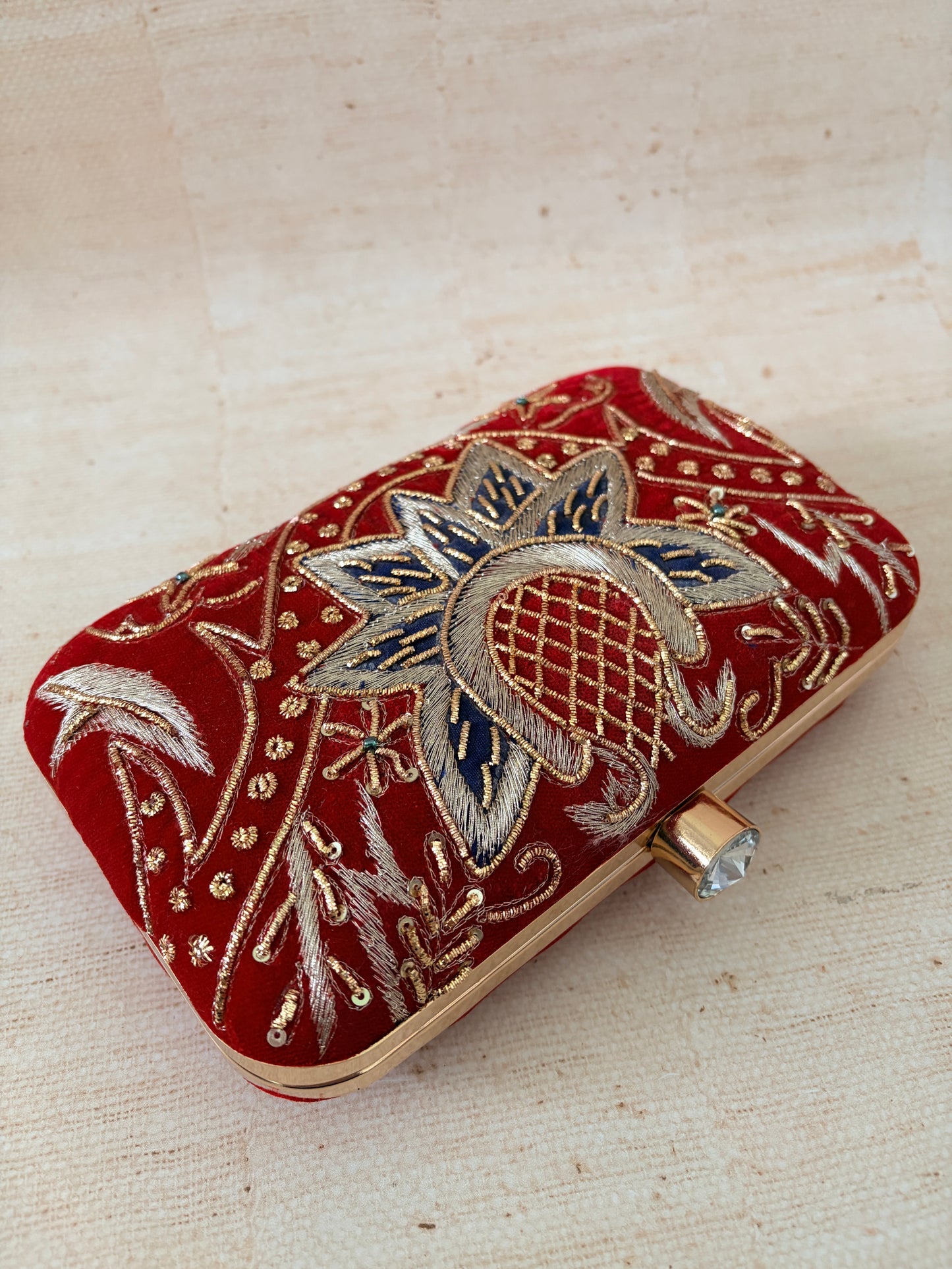 Decorative red clutch with floral patterns on a beige background