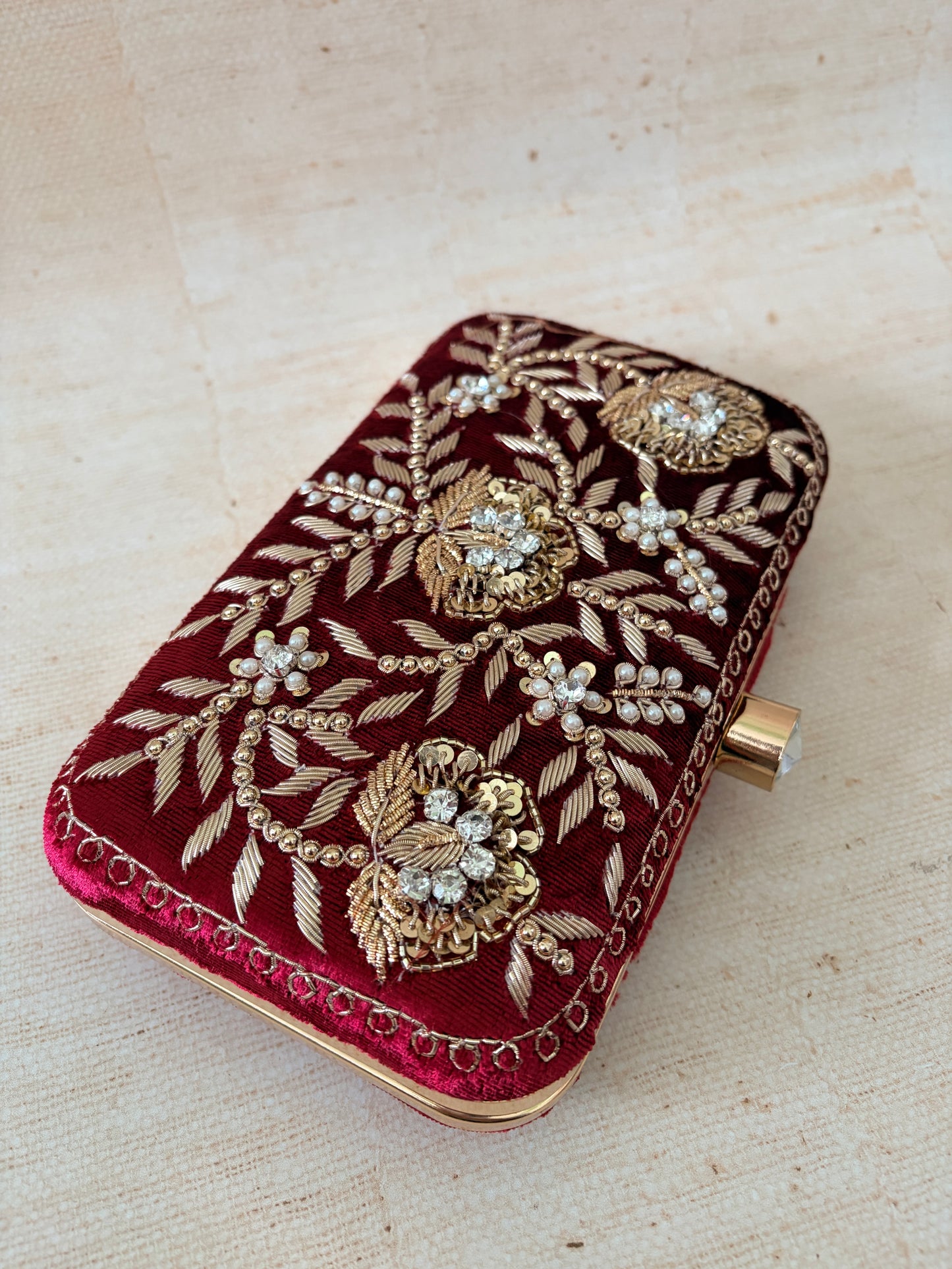 Decorative clutch bag with gold embroidery on a beige background