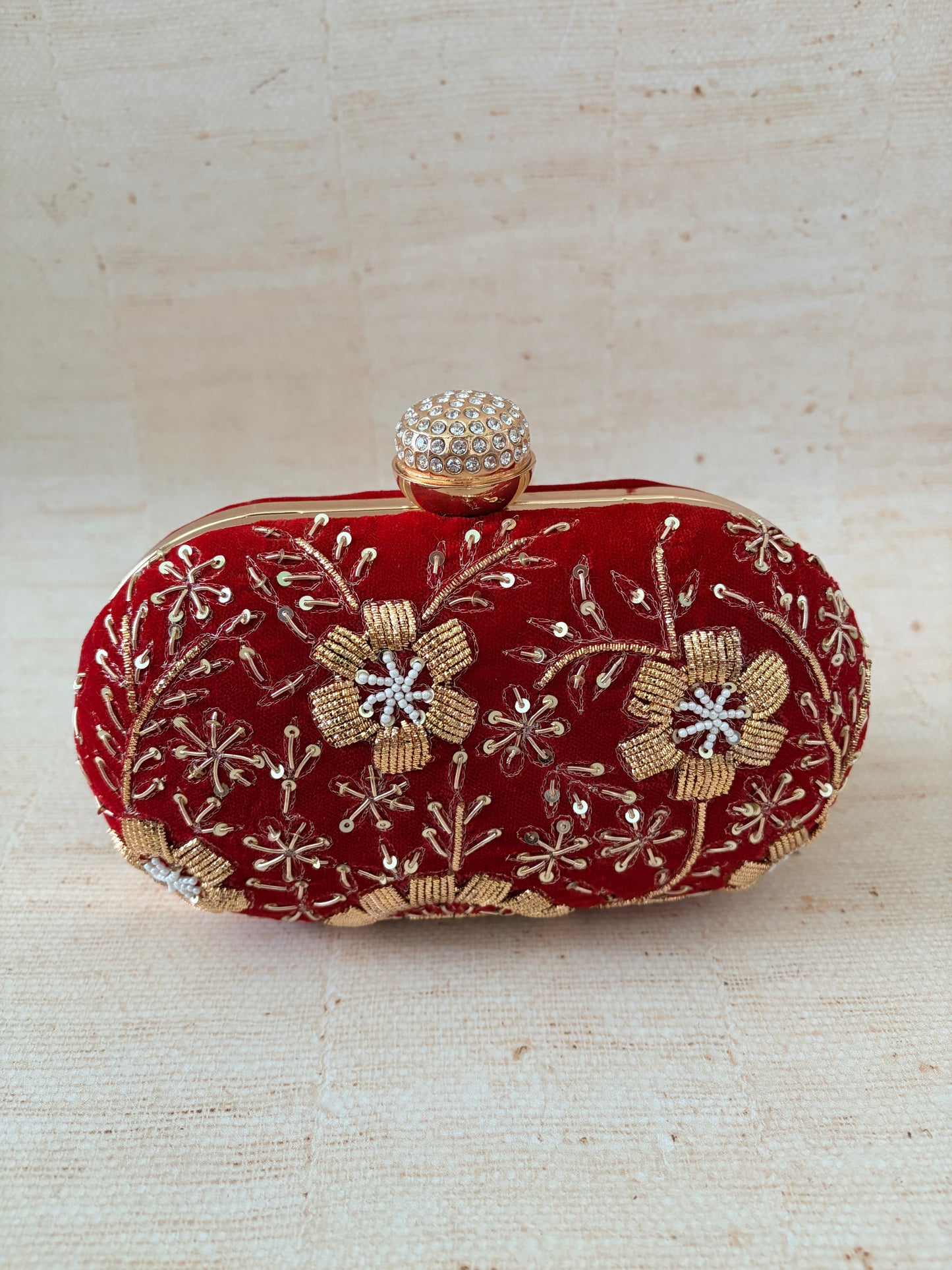 Red clutch with floral embroidery on a beige background