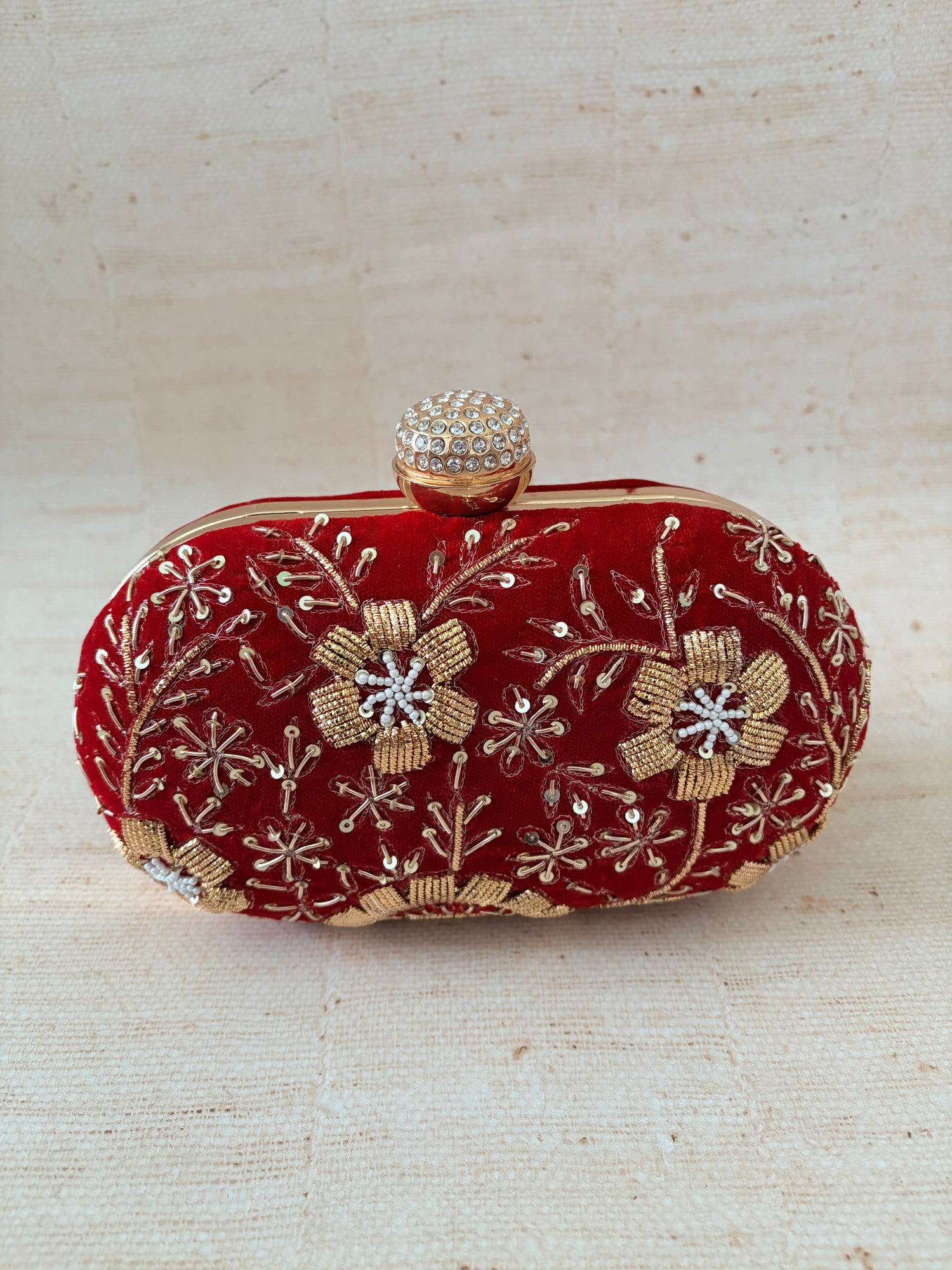 Red clutch with floral embroidery on a beige background