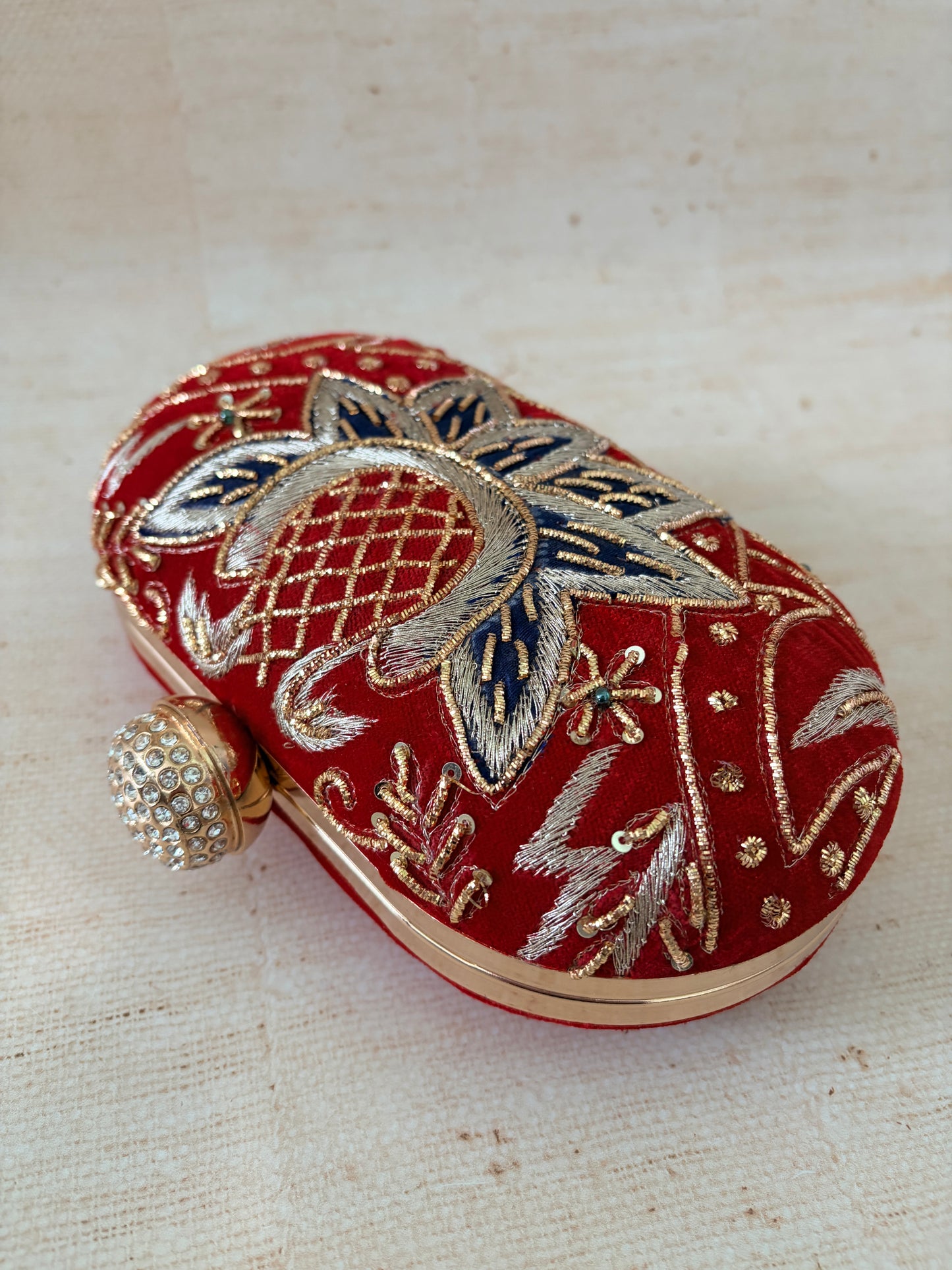 Decorative red pouch with gold and silver embroidery on a textured beige background