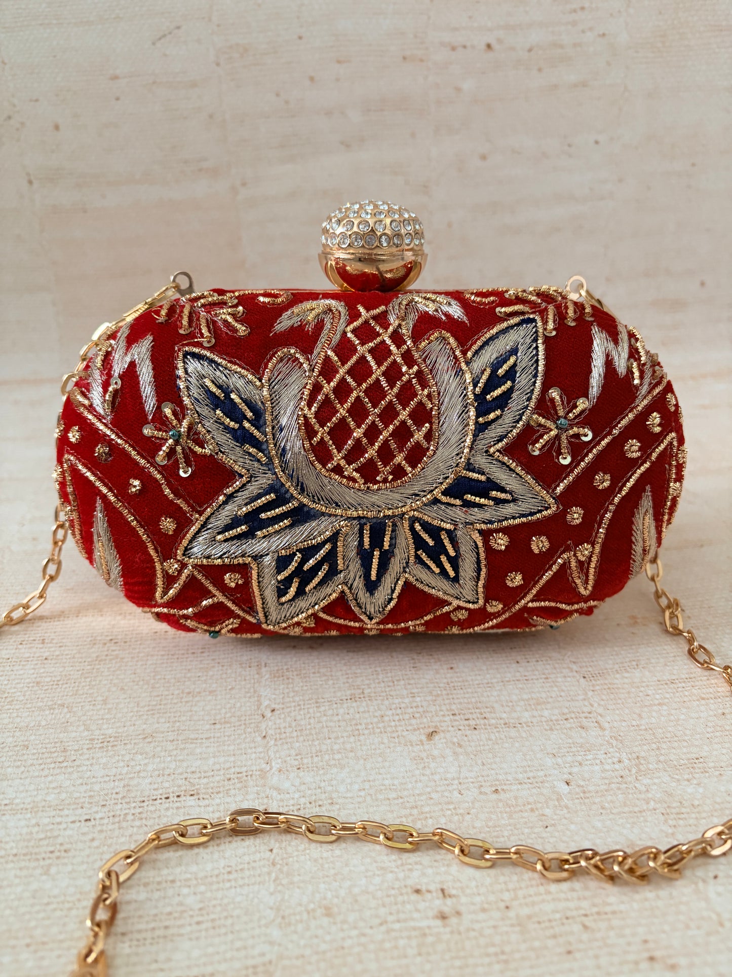 Decorative clutch bag with floral embroidery on a textured surface