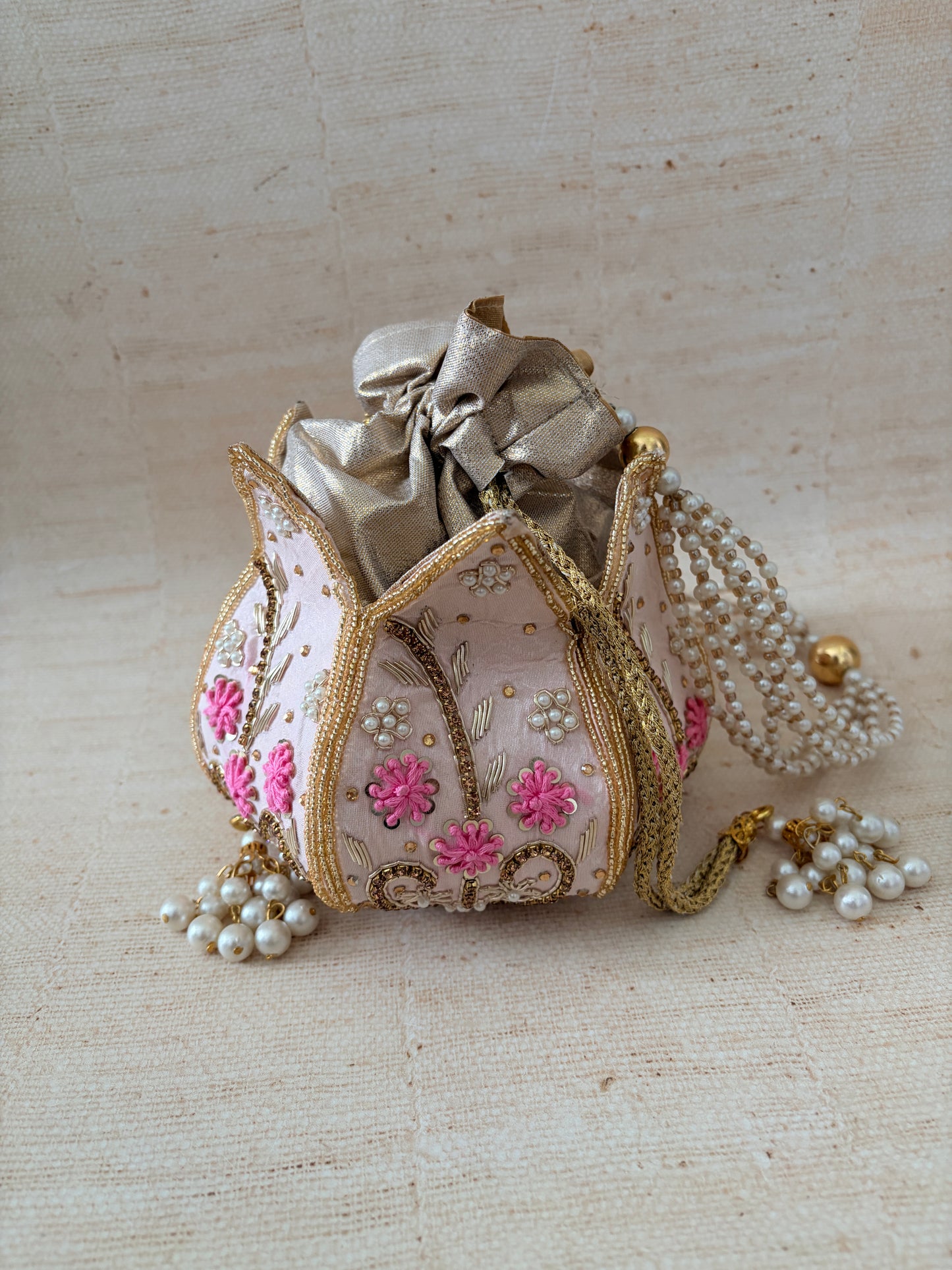 Decorative brooch with floral patterns and pearls on a textured beige background