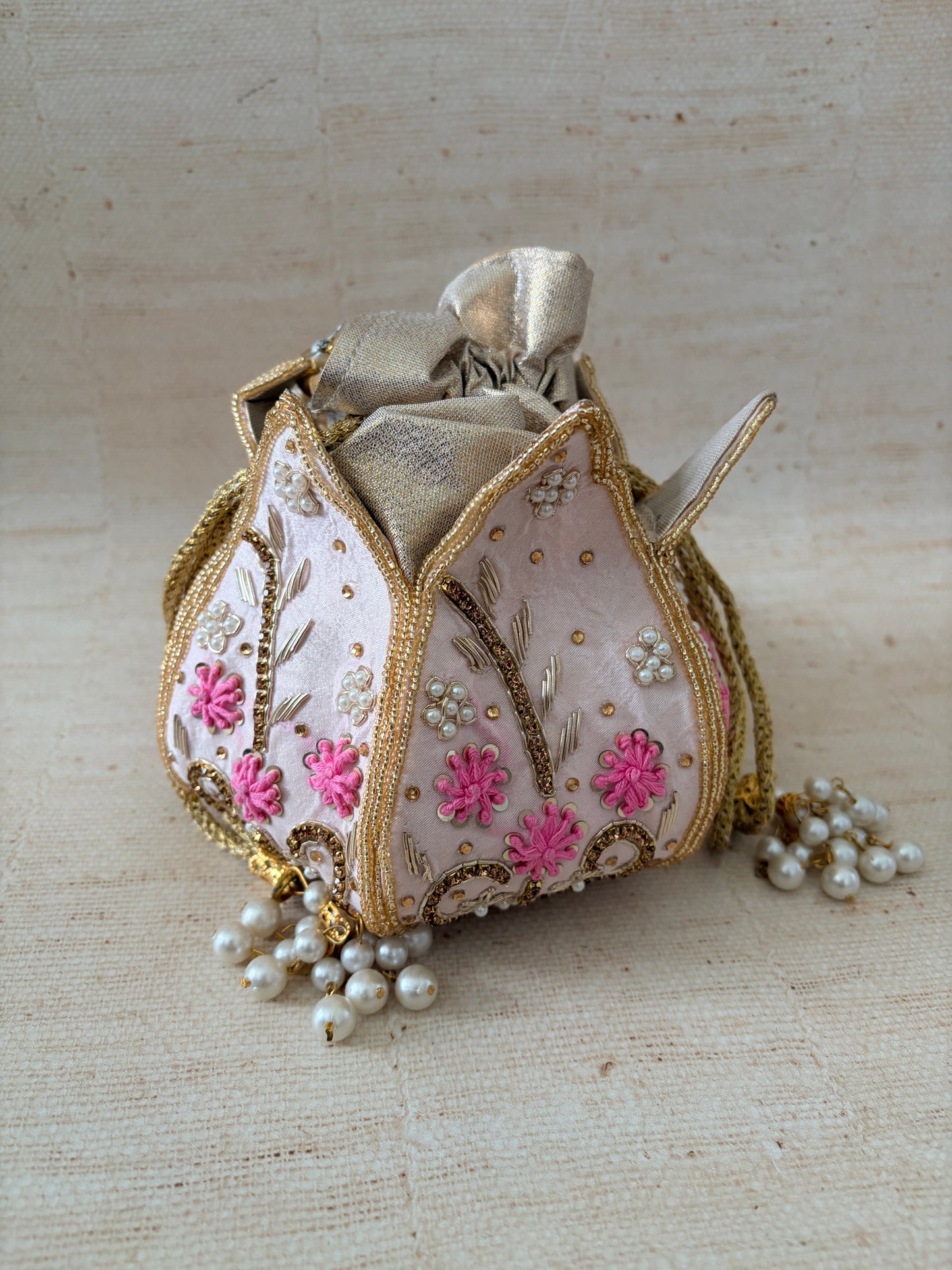 Decorative hair clip with floral and pearl details on a textured beige background