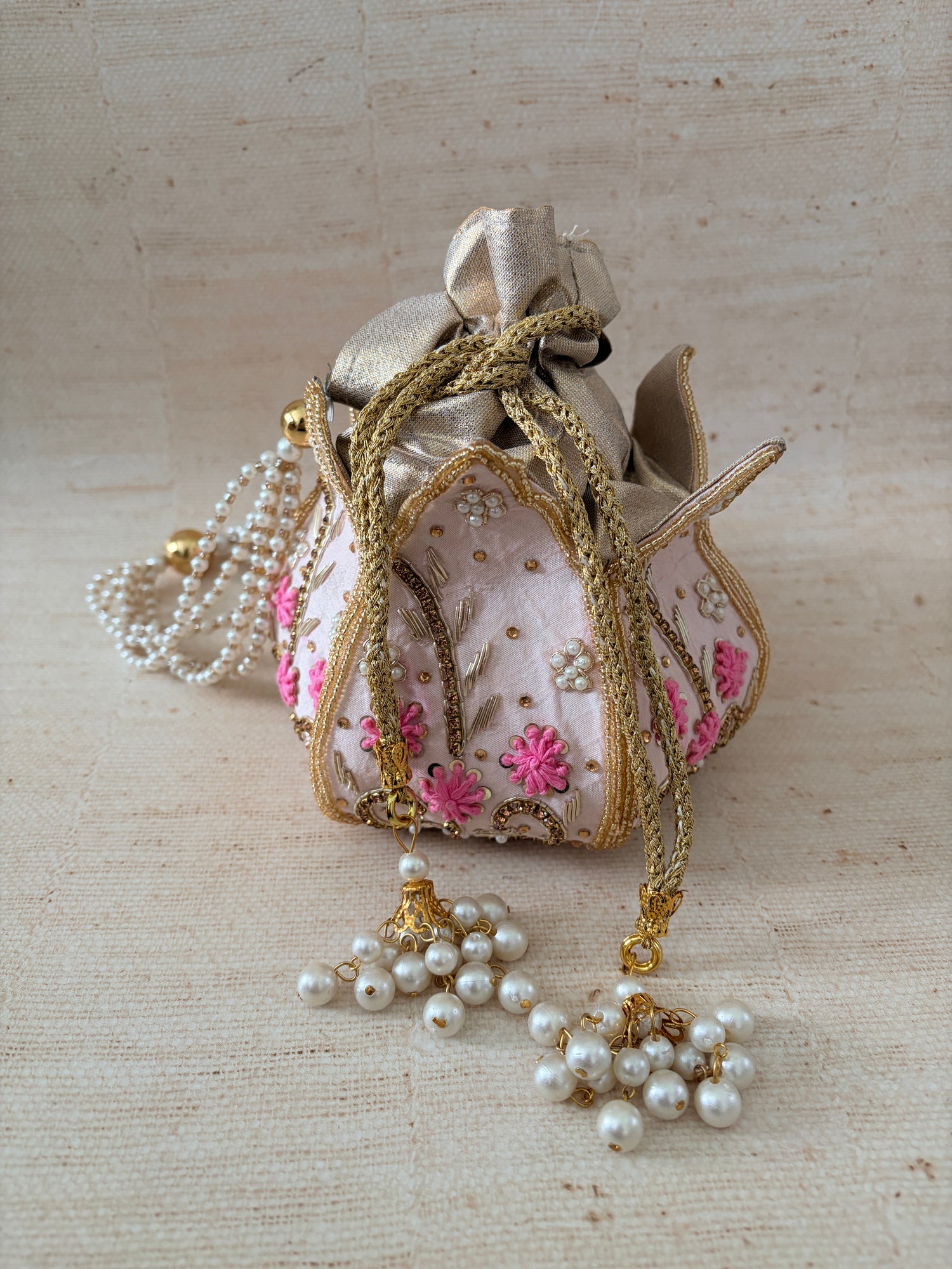 Decorative shoe with floral embroidery and pearl decorations on a textured beige background