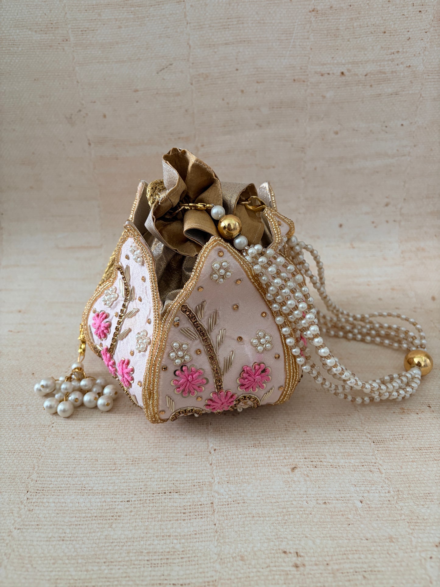 Decorative heart-shaped object with floral patterns and pearl accents on a beige background