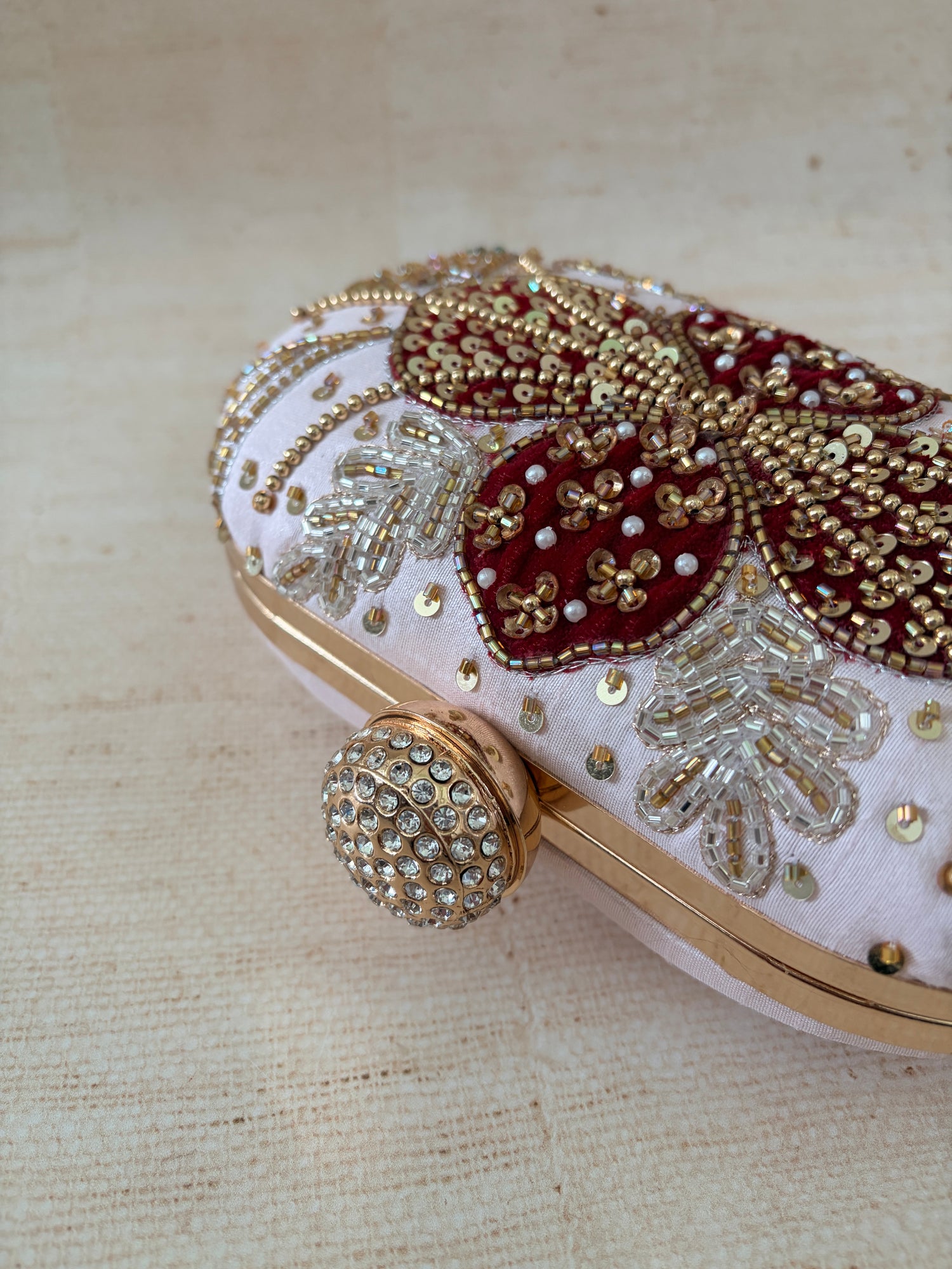 Decorative shoe with gold and red embellishments on a beige background