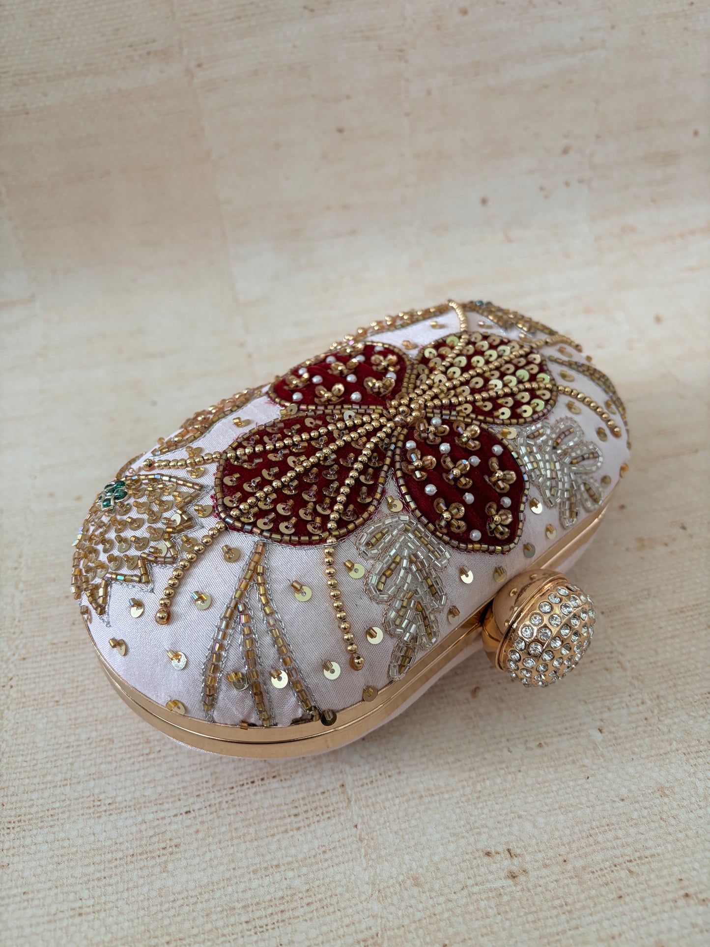 Decorative sandal with gold and red embellishments on a beige fabric background