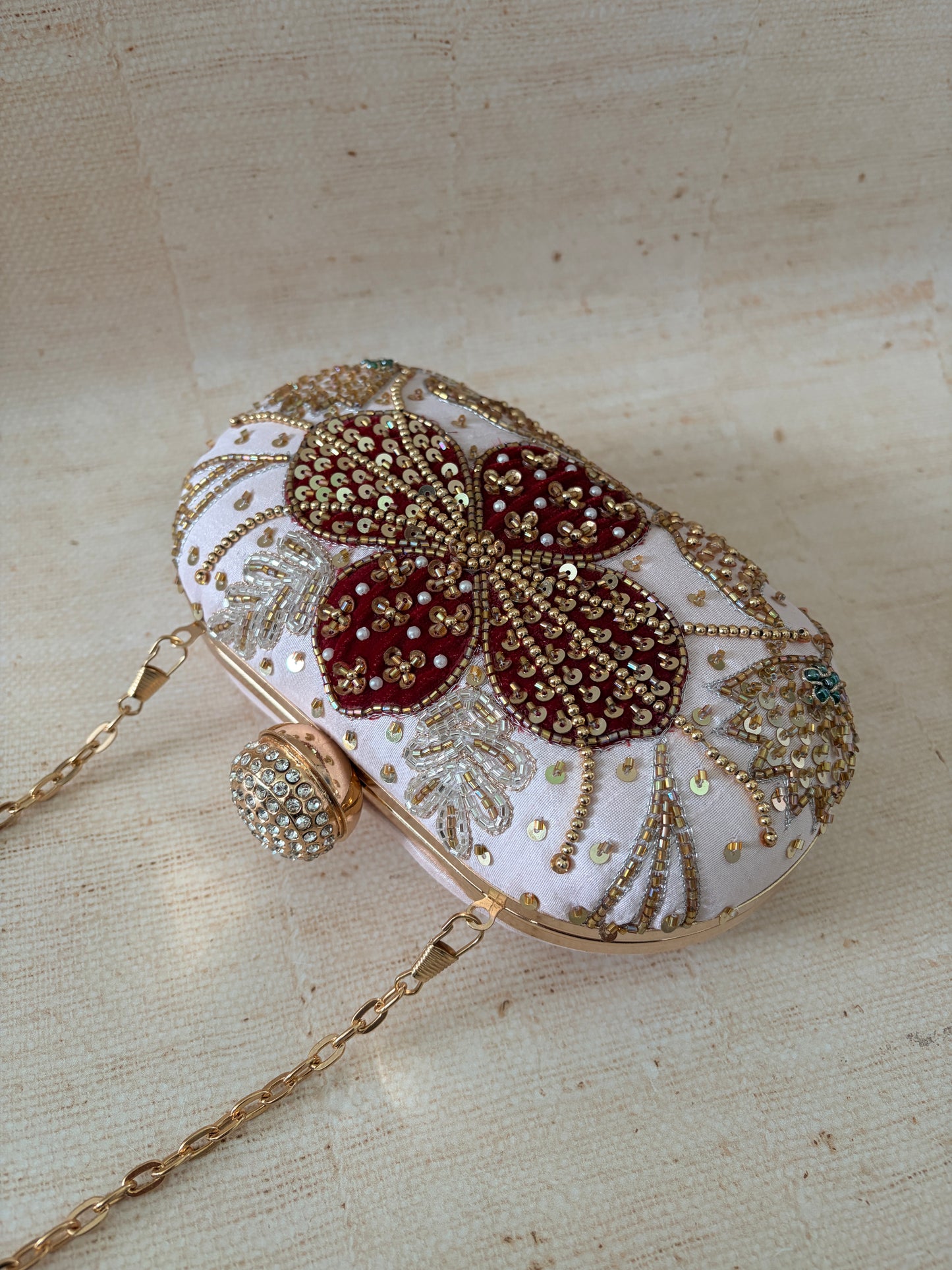 Decorative handbag with butterfly design and embellishments on a beige fabric background