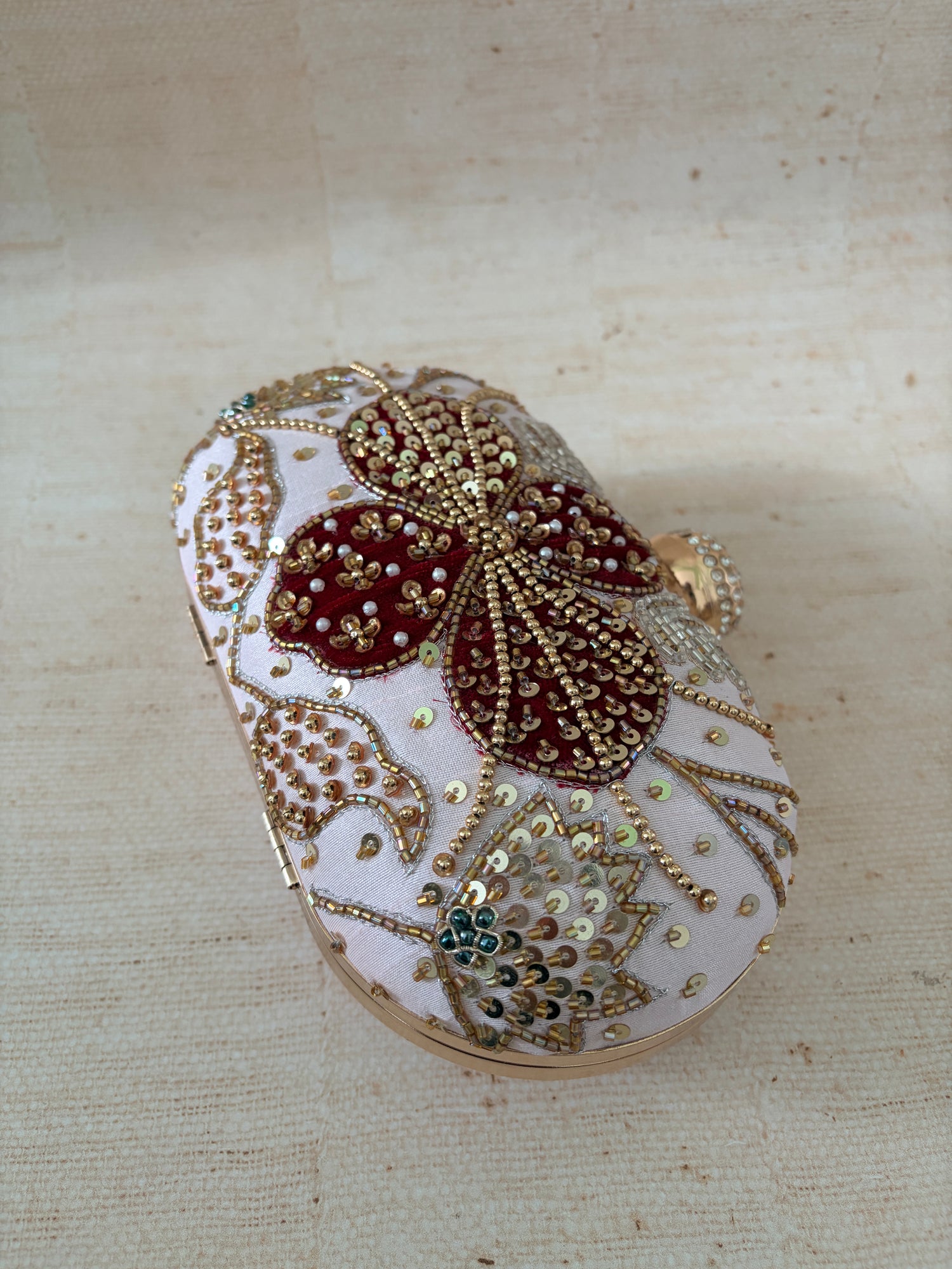 Decorative clutch bag with floral patterns on a beige fabric background