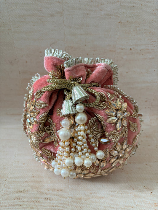 Decorative headband with pink fabric, gold leaves, and pearls on a beige background