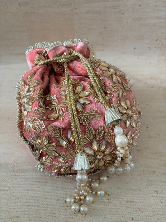 Decorative headpiece with pink fabric, gold embroidery, and pearl accents on a beige background
