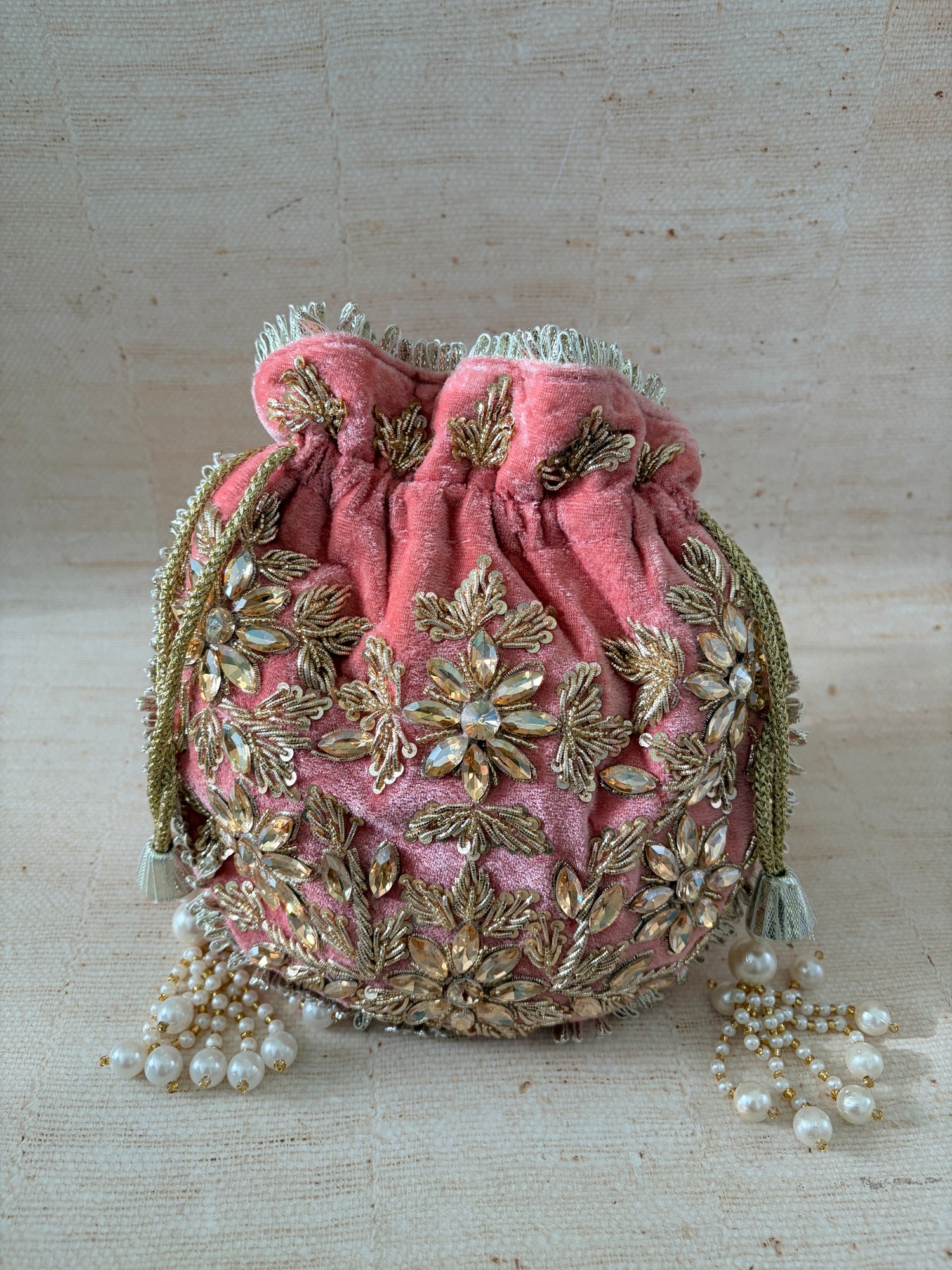 Pink velvet bag with gold embroidery on a beige background