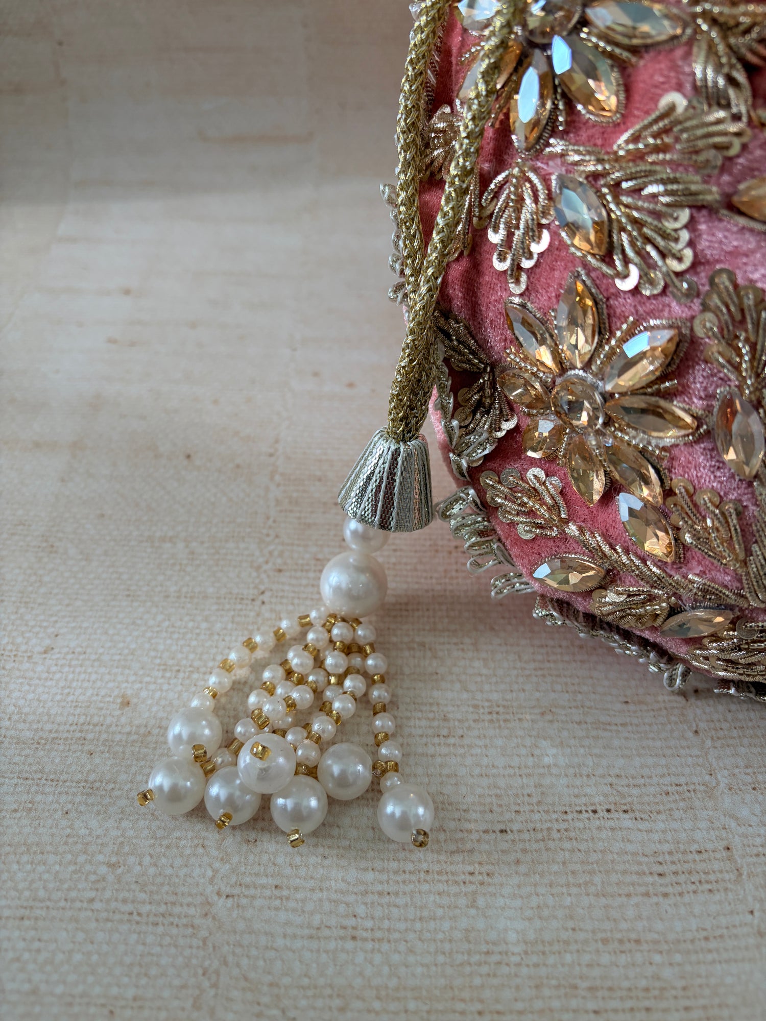 Decorative headband with gold embellishments and a pearl earring on a textured beige background