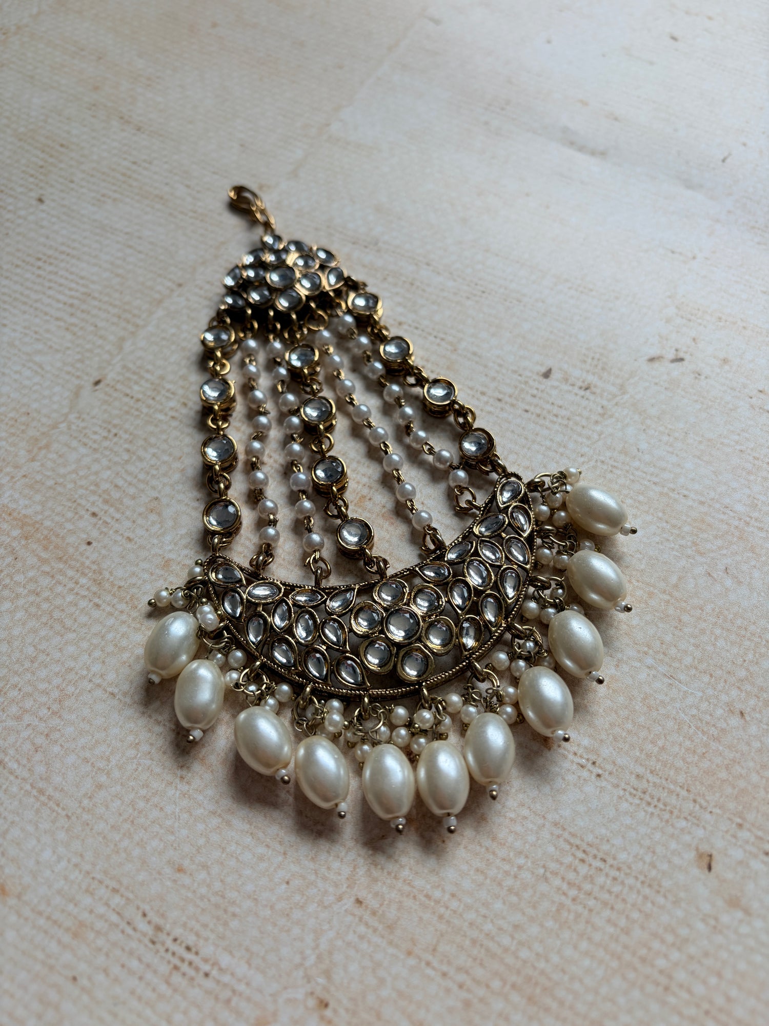 Pearl and crystal brooch on a textured beige background