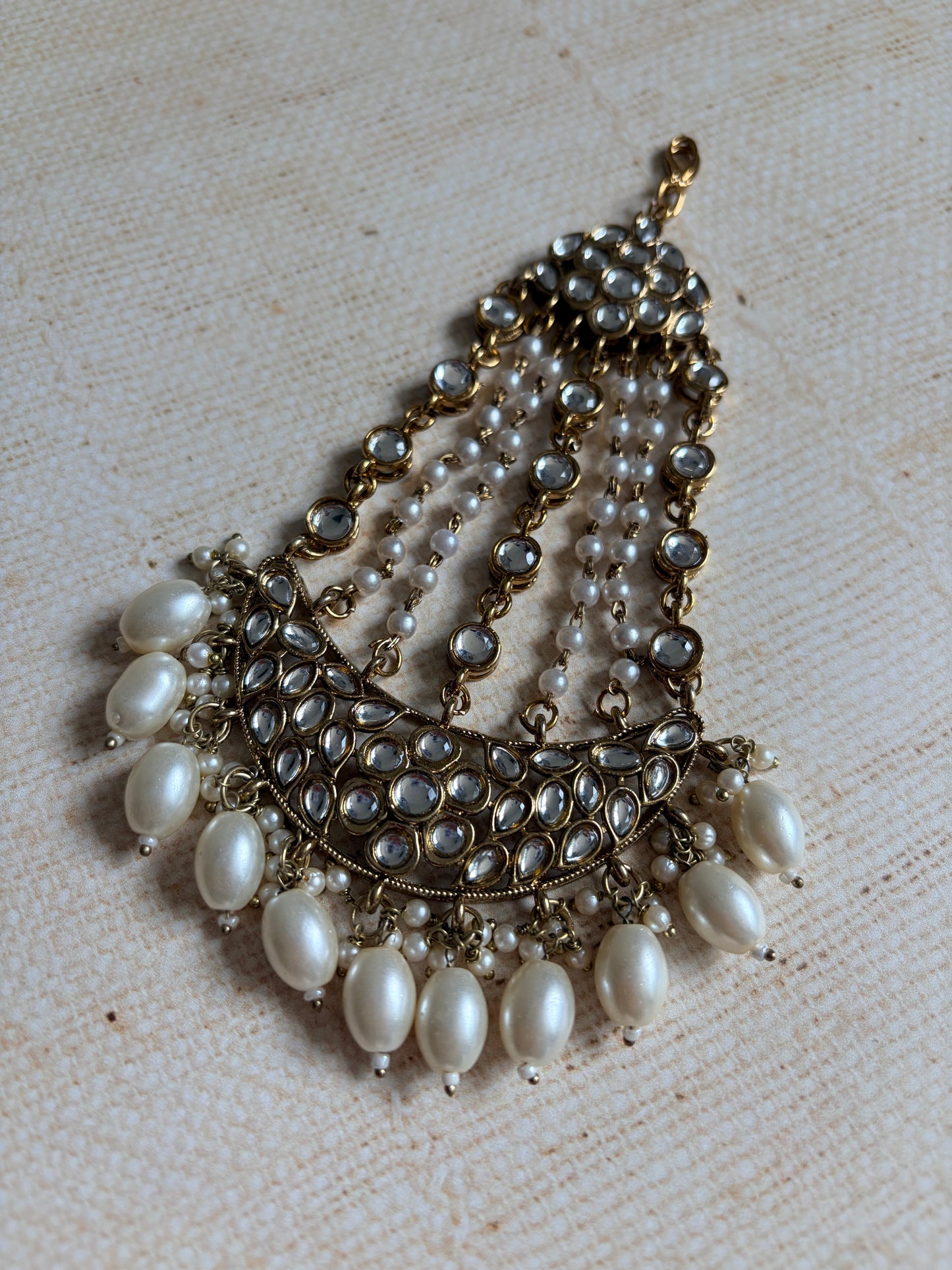 Pearl necklace with gold accents on a textured beige background