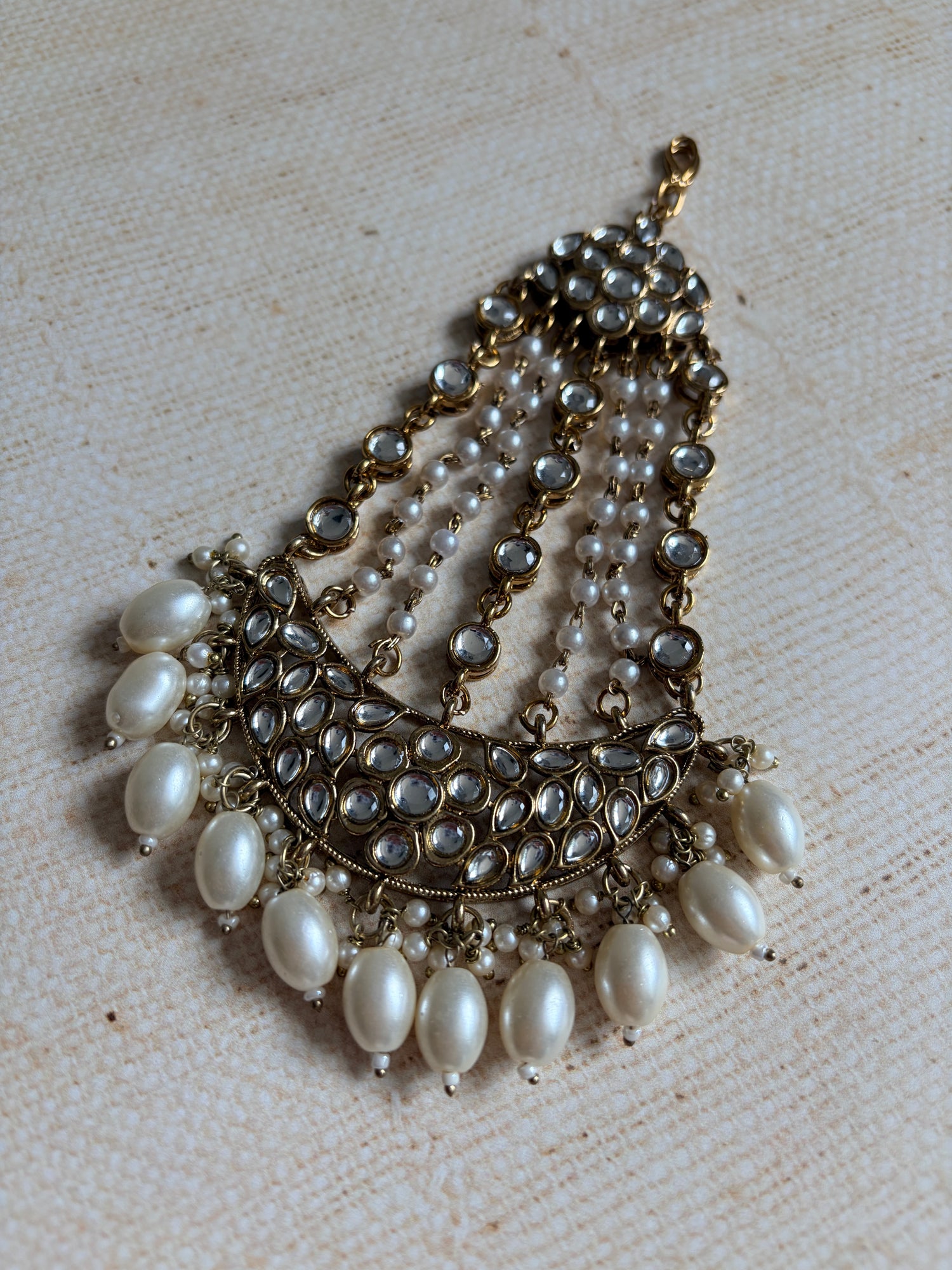 Pearl necklace with gold accents on a textured beige background