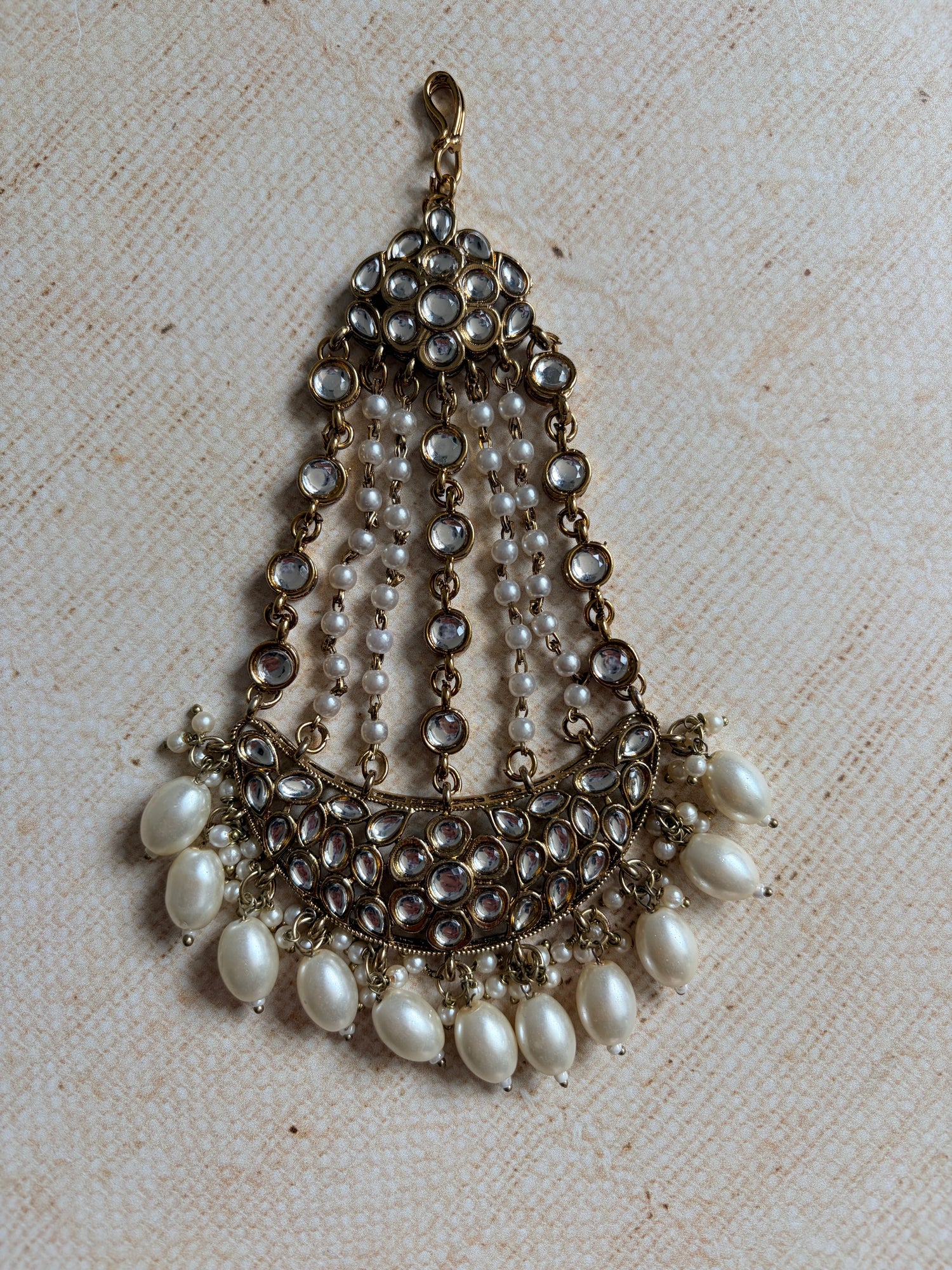 Decorative pendant with pearls and crystals on a textured beige background