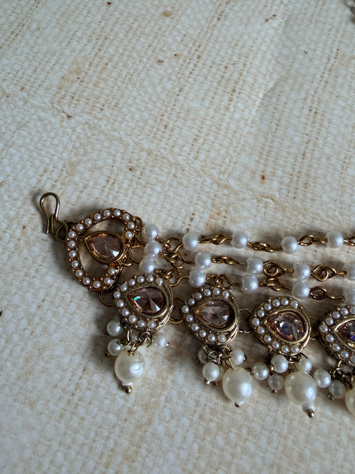 Pearl and gold necklace on a textured beige background