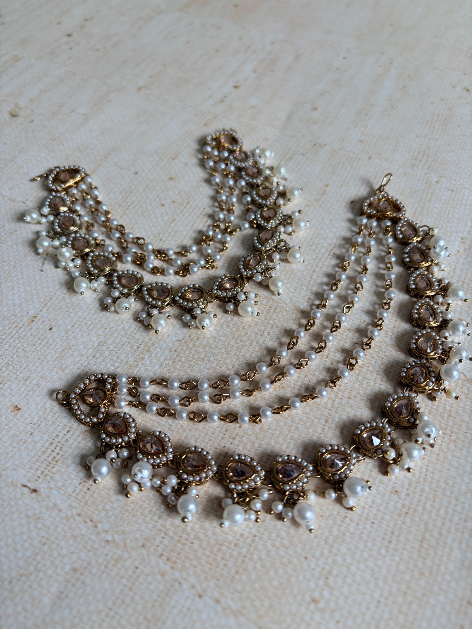 Pearl and gold necklace on a textured beige surface