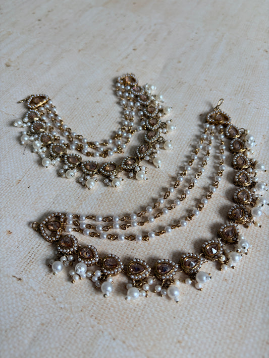 Pearl and gold necklace on a textured beige surface