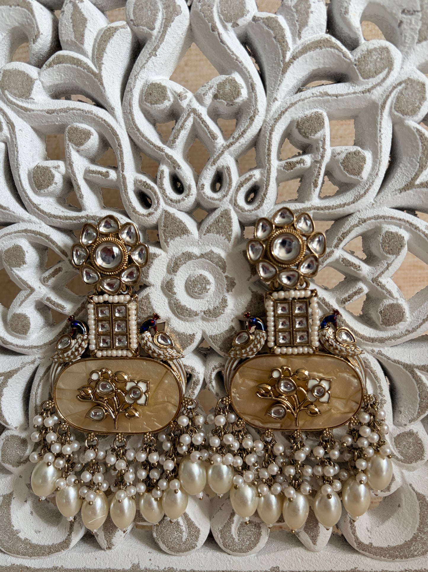 Decorative brooch with pearls and intricate design on a textured background