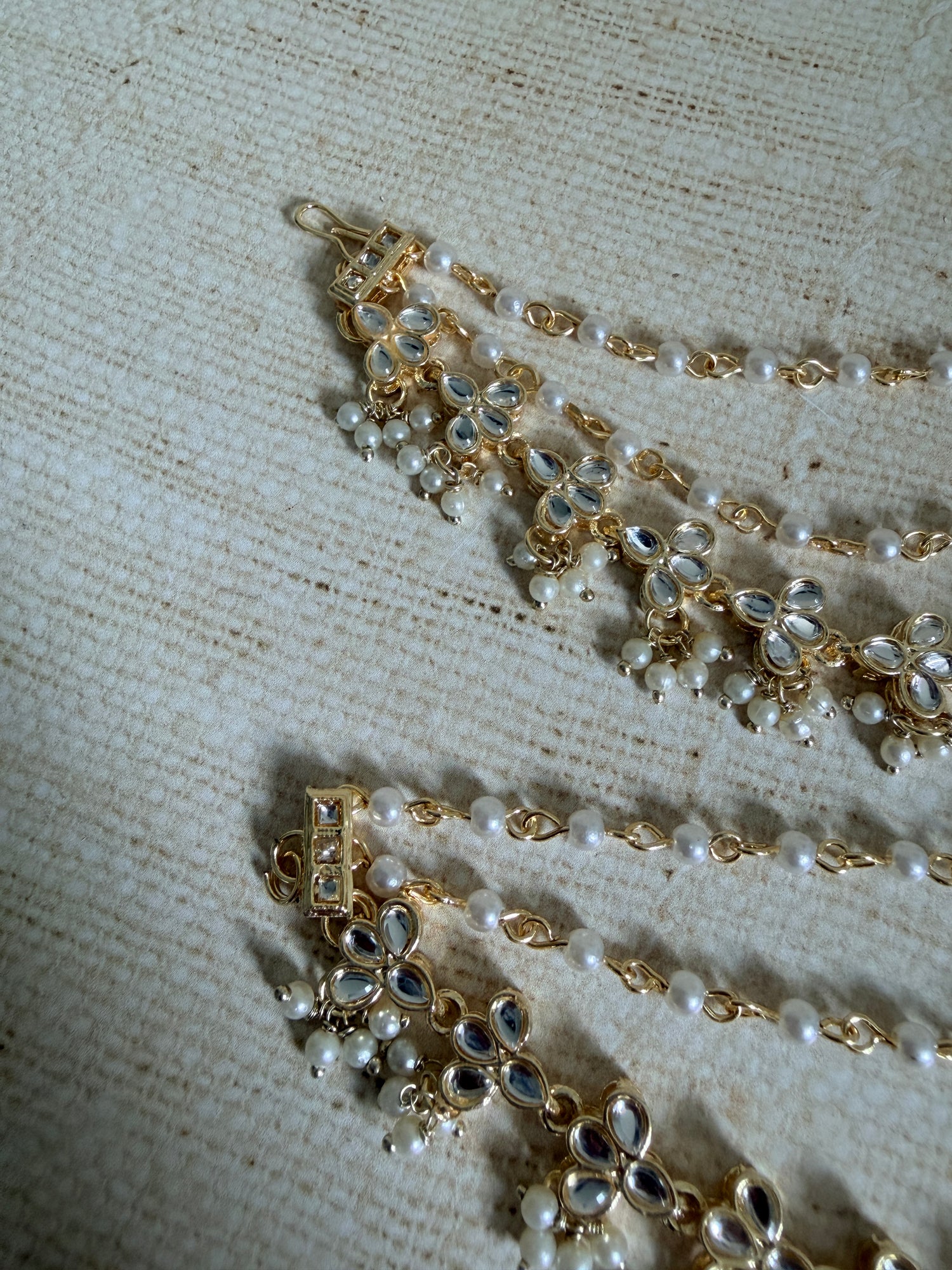 Gold and pearl jewelry set on a textured fabric background