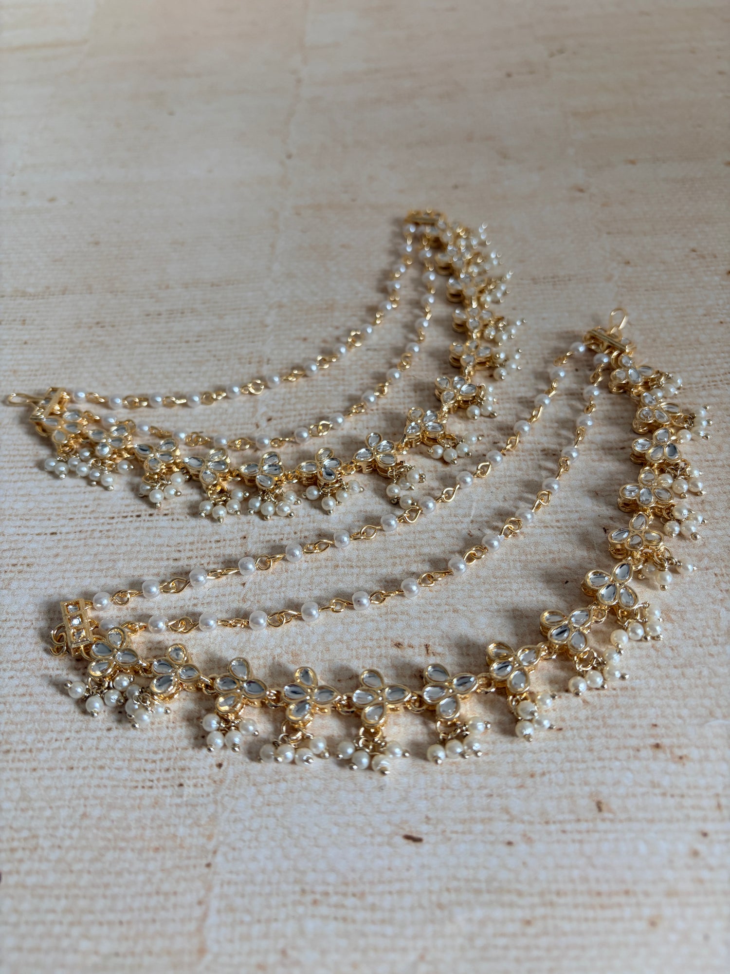 Delicate gold and pearl necklace on a textured beige background