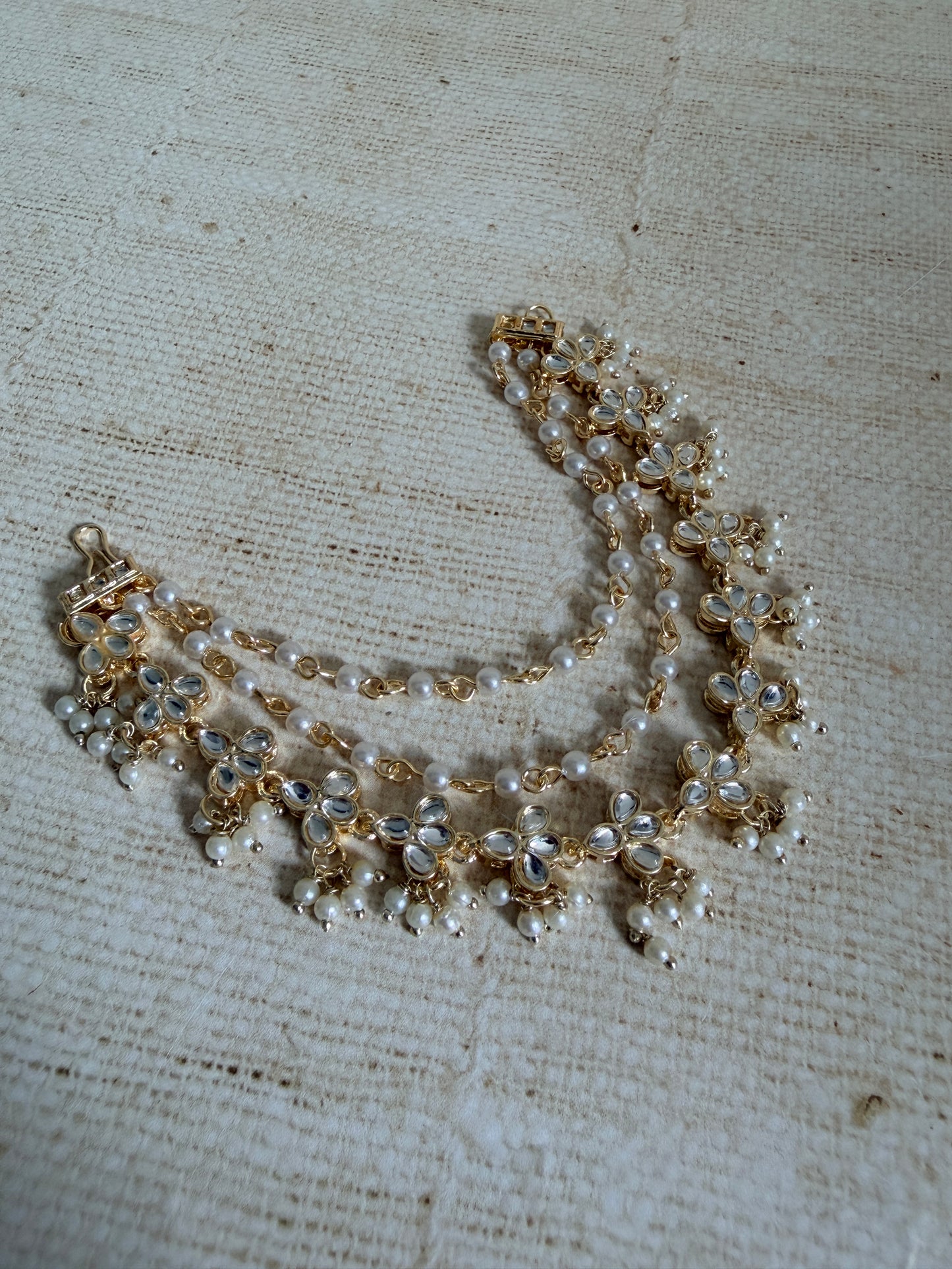 Pearl and gold necklace on a textured beige fabric background