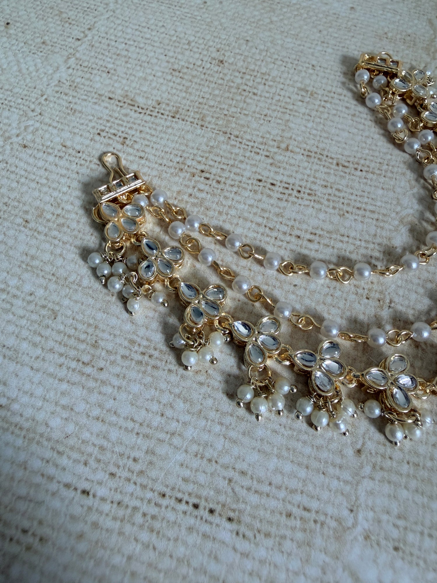 Gold and pearl necklace on a textured fabric background