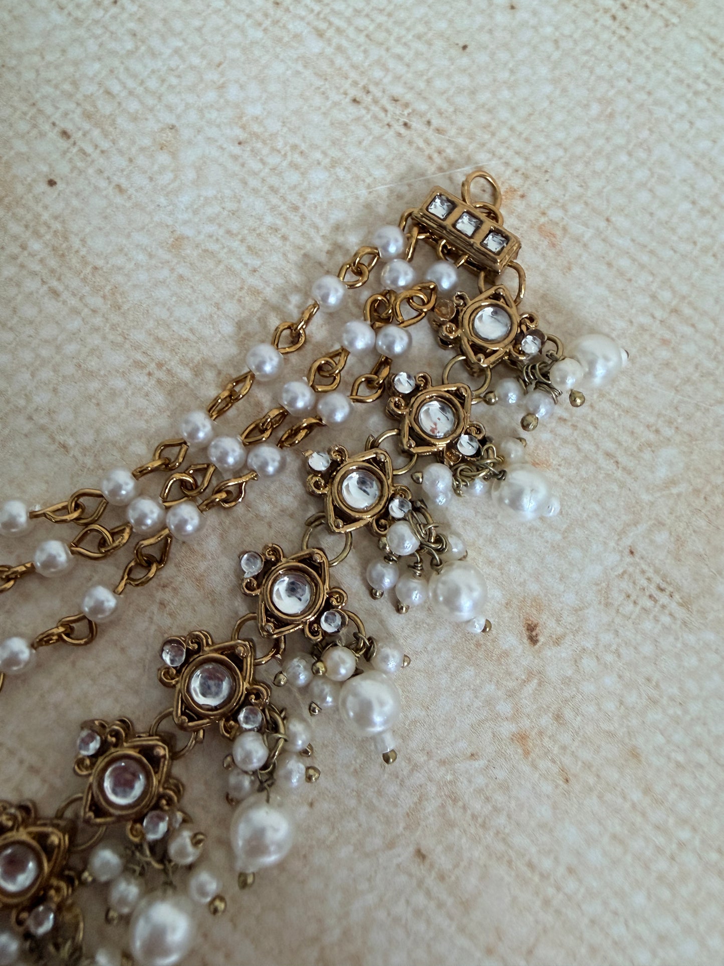 Pearl and gold necklace on a textured beige surface