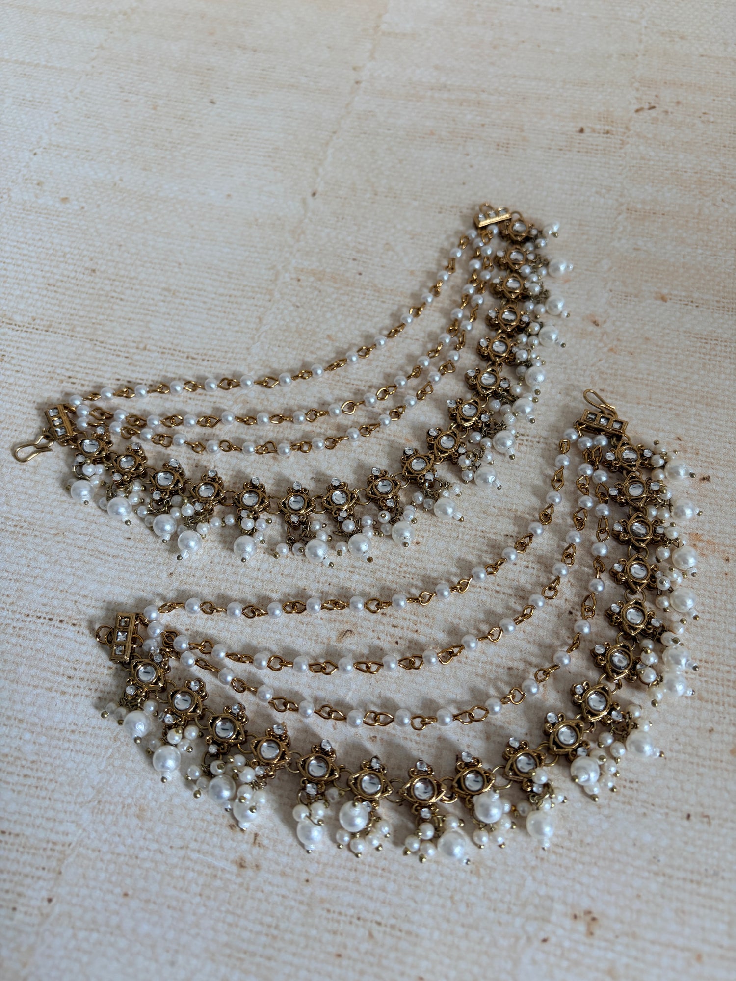 Two pearl necklaces on a textured beige surface