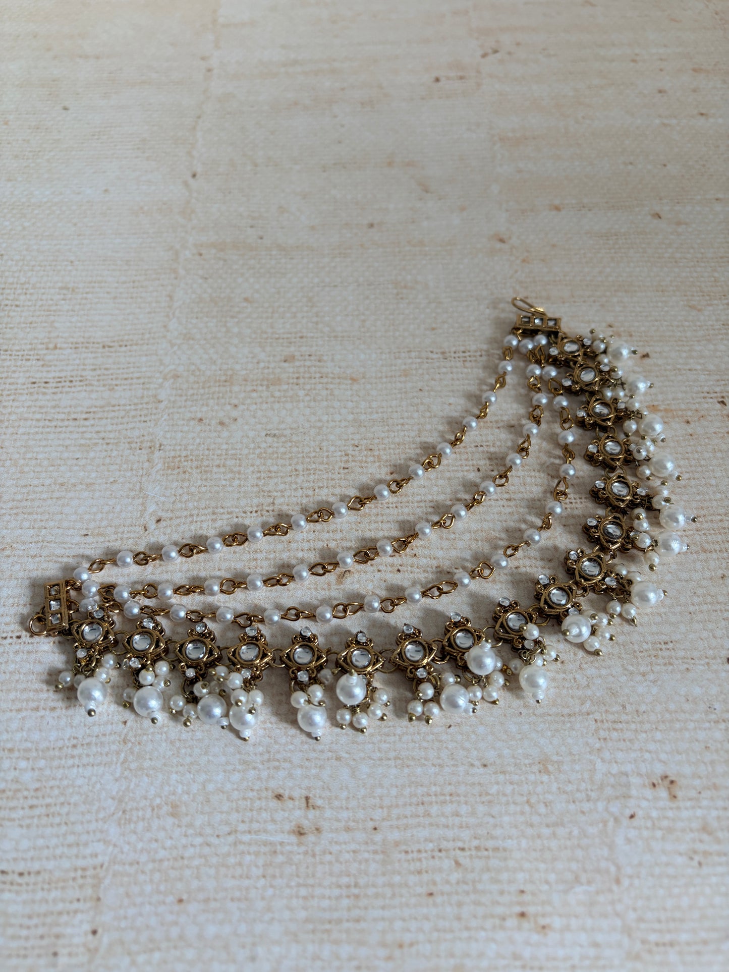 Pearl necklace with gold accents on a textured beige background
