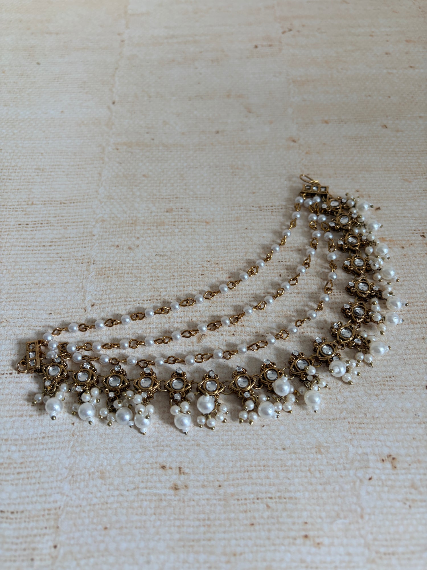 Pearl necklace with gold accents on a textured beige background