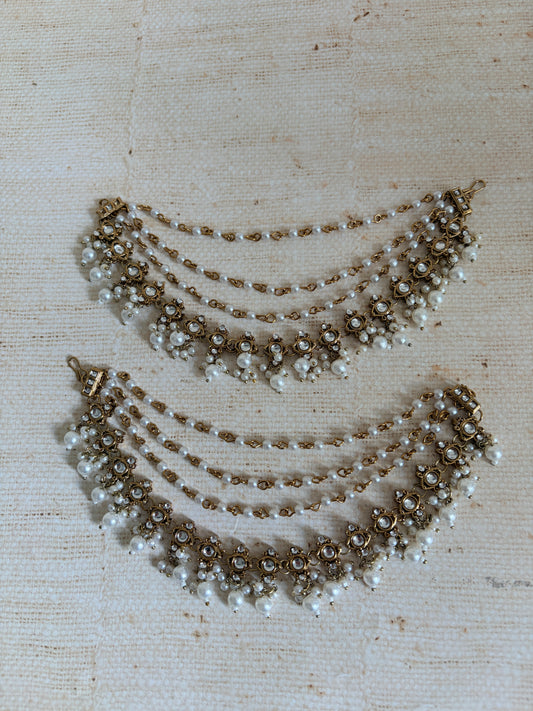 Two pearl necklaces on a textured beige fabric background