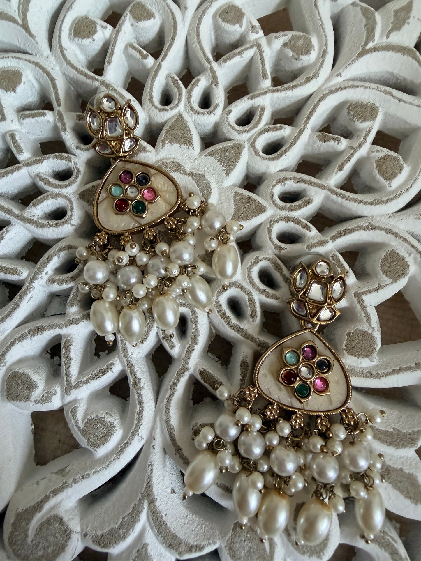 Heart-shaped jewelry with pearl and gemstone details on an ornate white background