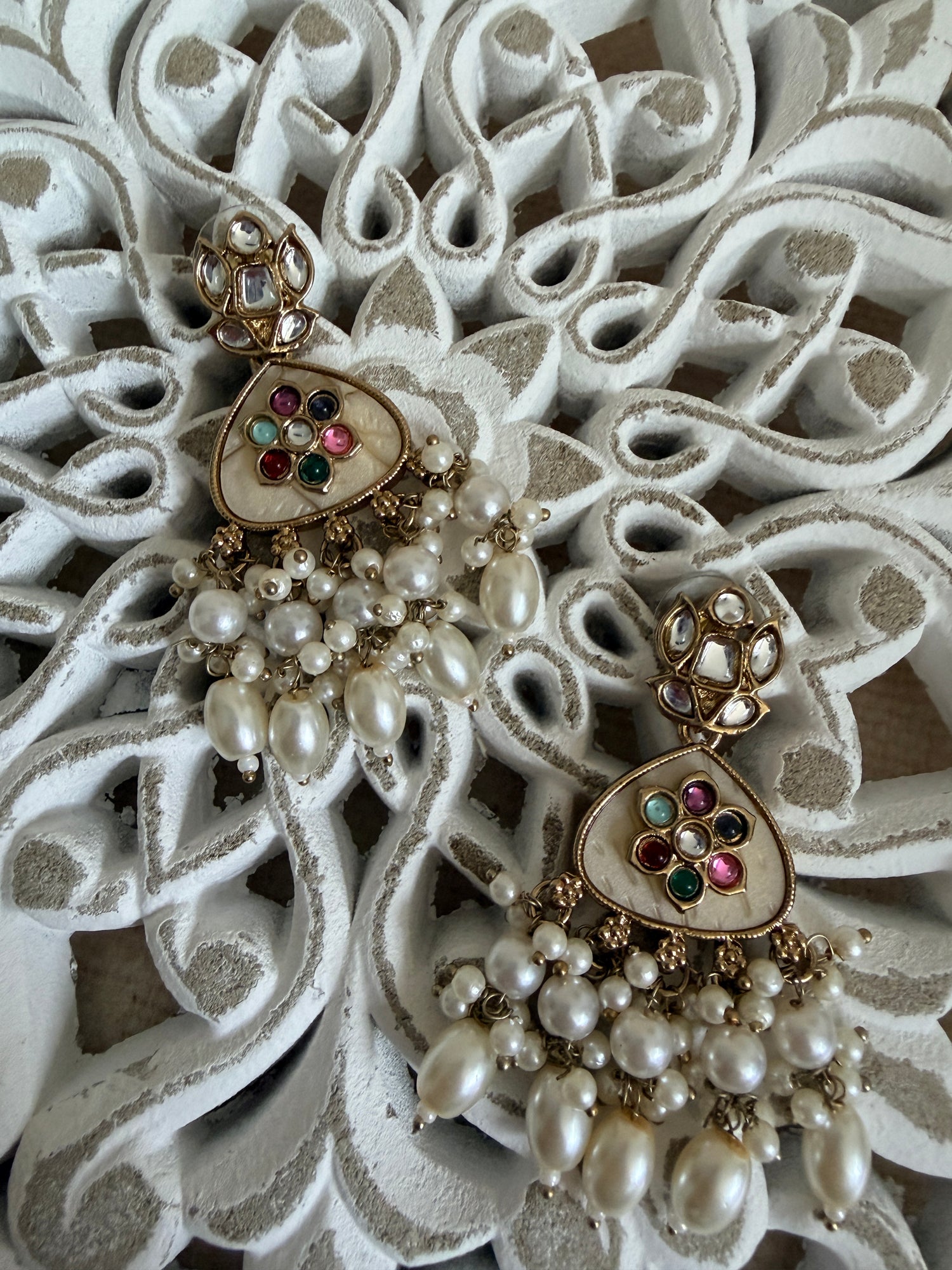 Heart-shaped jewelry with pearl and gemstone details on an ornate white background