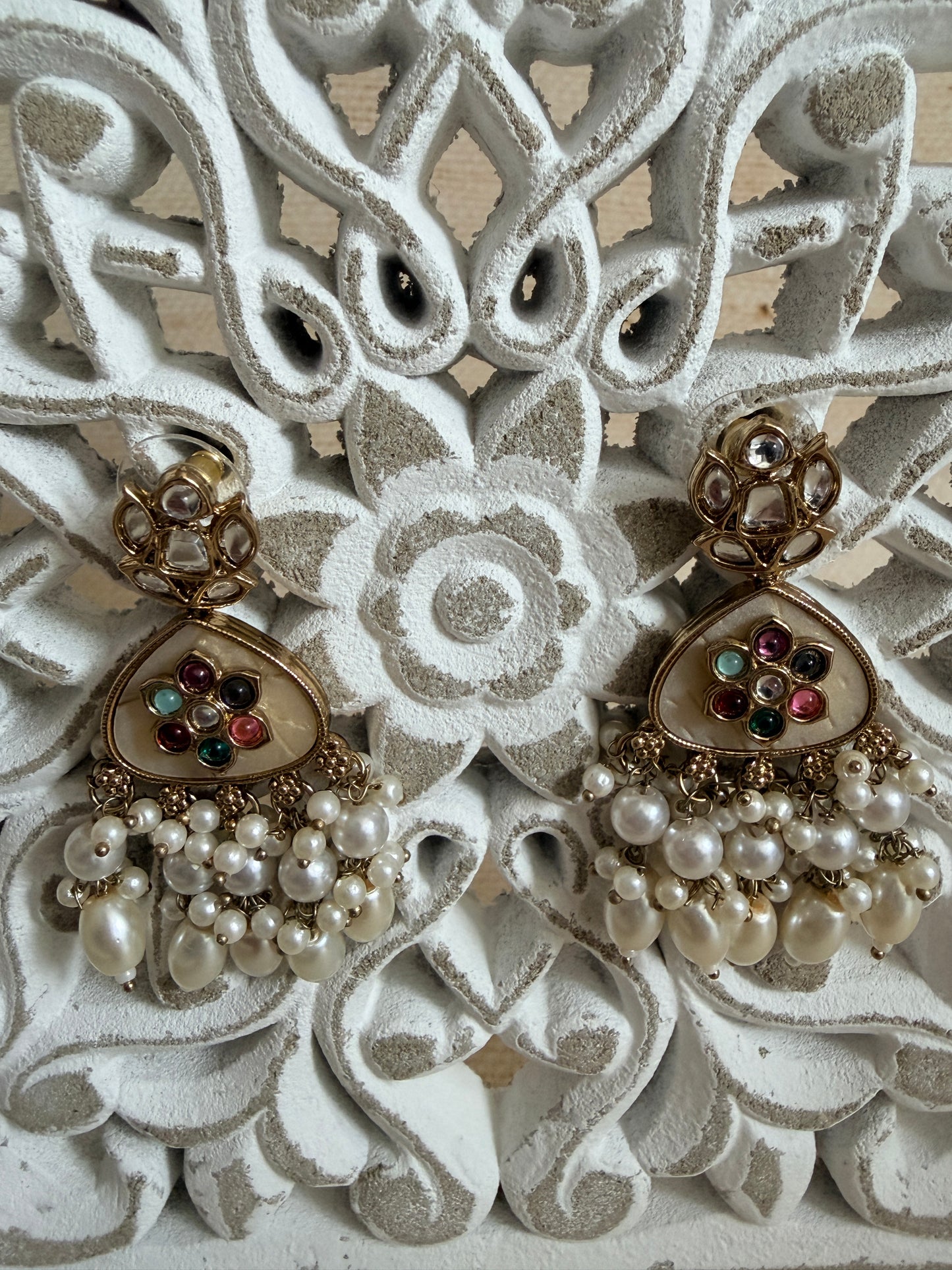 Pair of pearl earrings with heart designs on an ornate white background