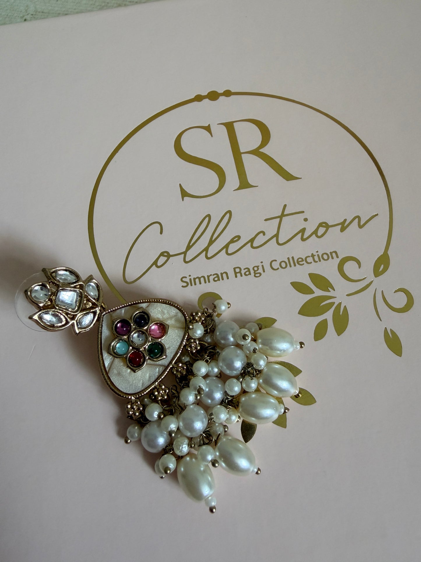 Jewelry brooch with pearls and gemstones on a branded background