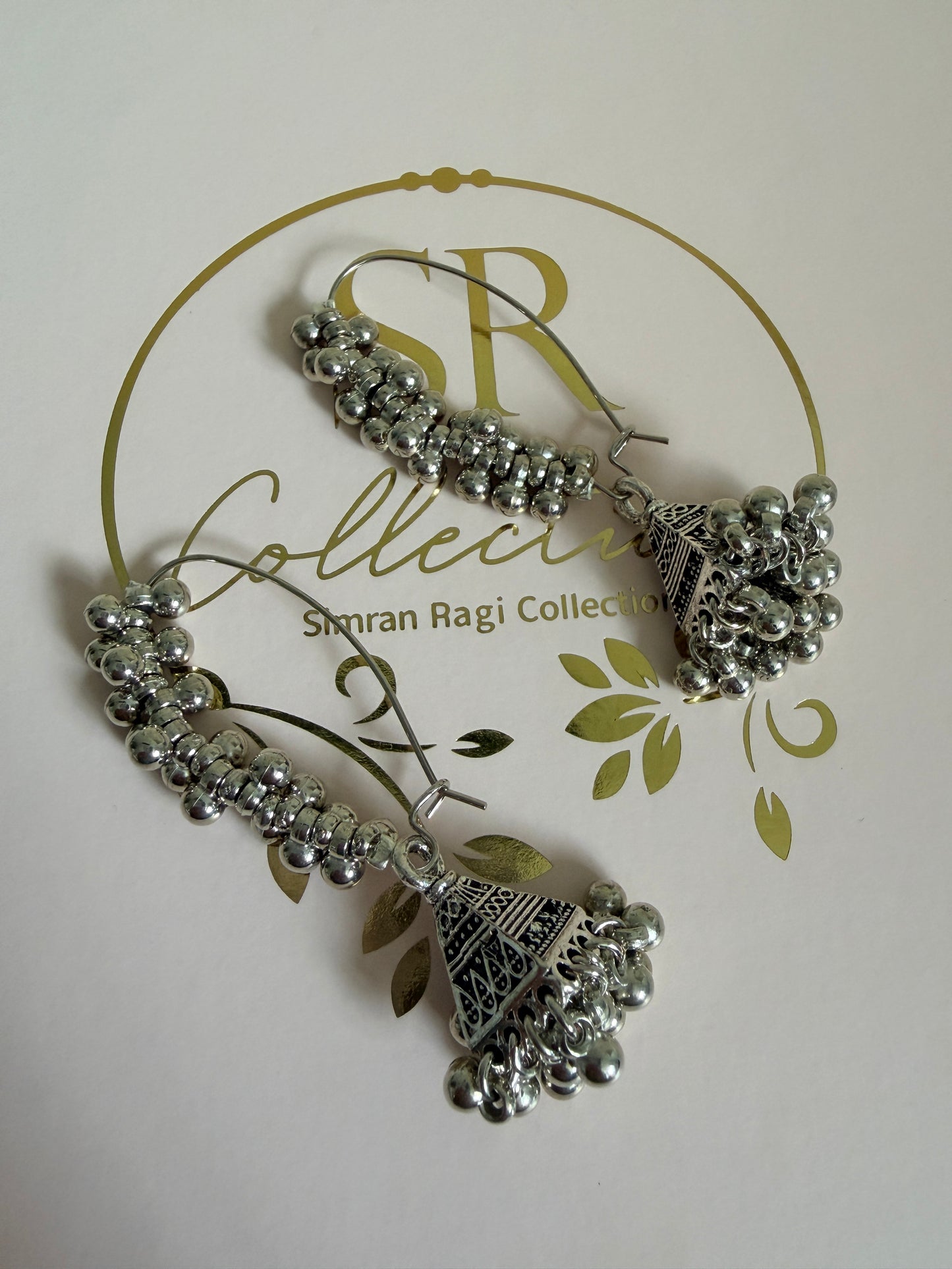 Silver earrings on a branded card with decorative elements
