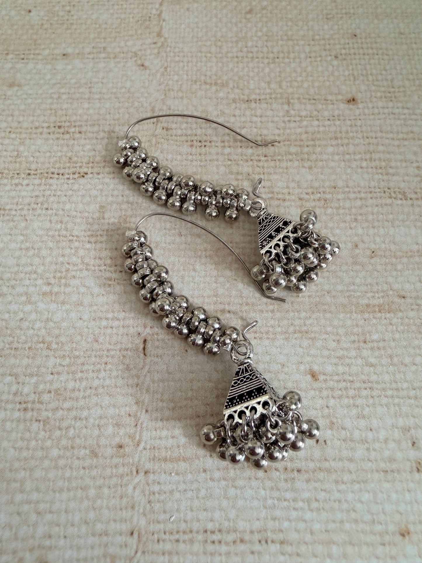 Pair of silver earrings on a textured beige background