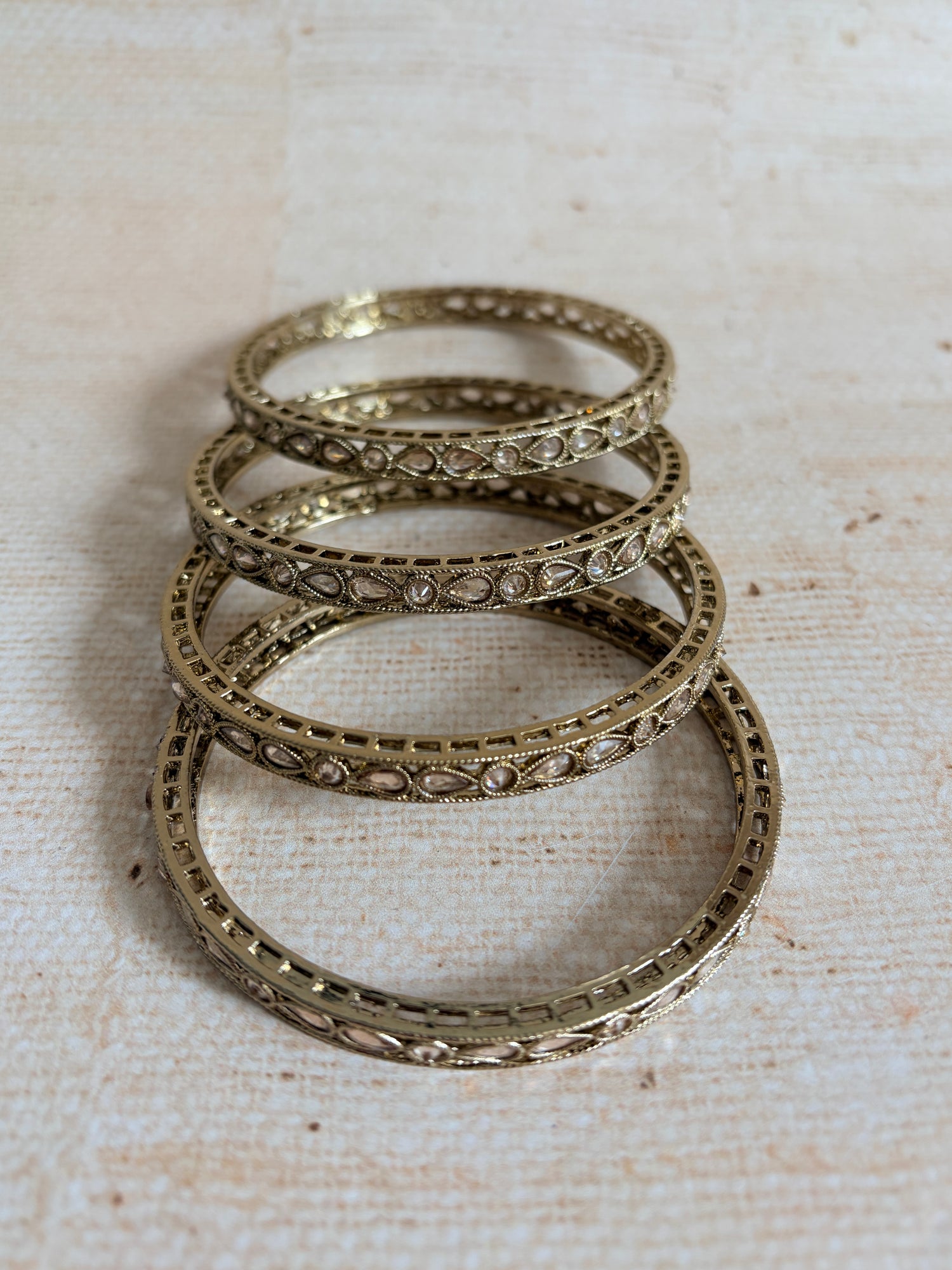 Three ornate silver rings stacked on a textured beige surface