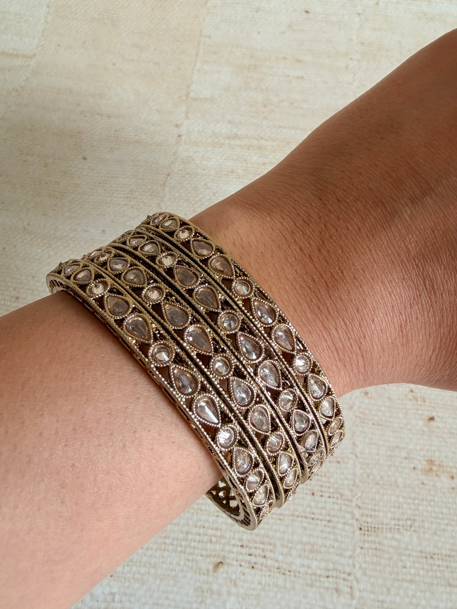 Decorative bracelet with gemstones on a wrist against a neutral background