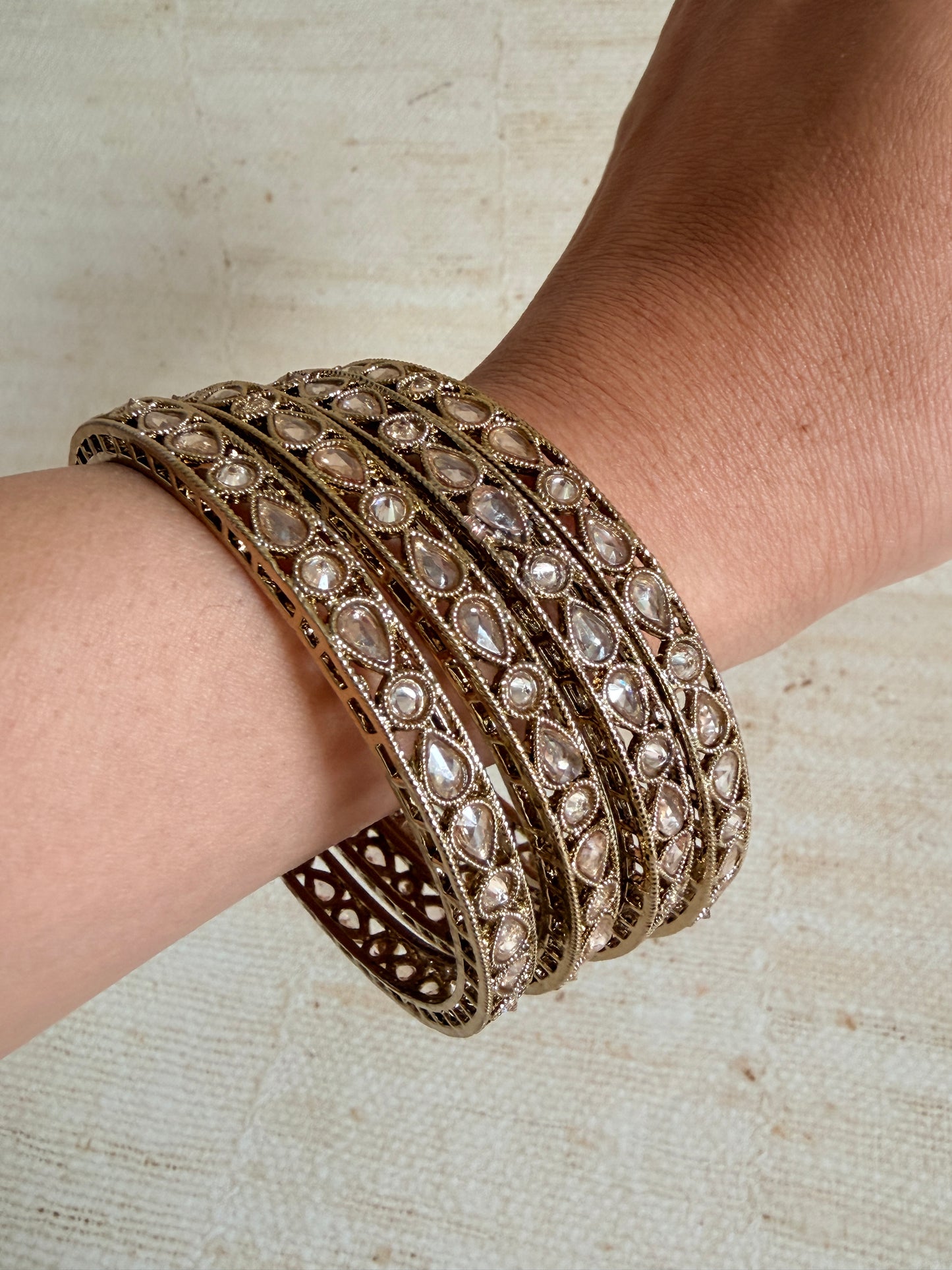Close-up of a person's wrist wearing a decorative bracelet with gemstones on a neutral background.