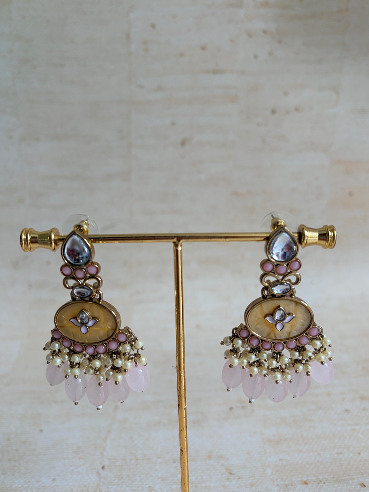 Pair of gold earrings with floral designs and gemstones on a light background