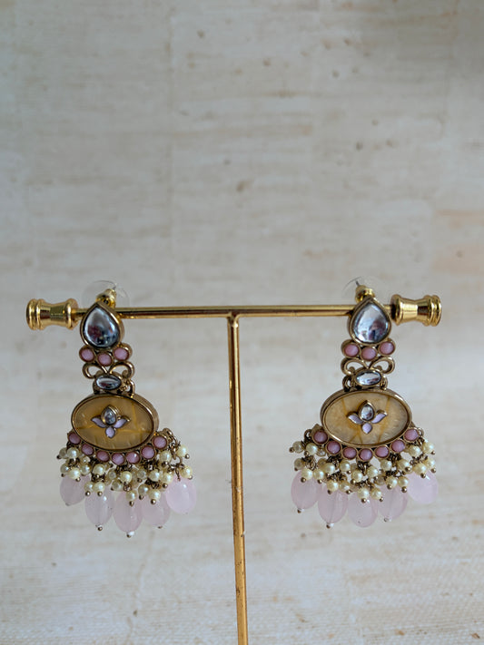 Pair of gold earrings with floral designs and gemstones on a light background