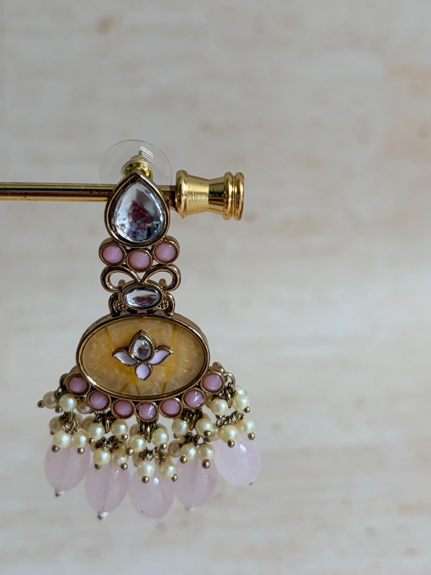 Decorative brooch with gold, pink, and pearl details on a light background