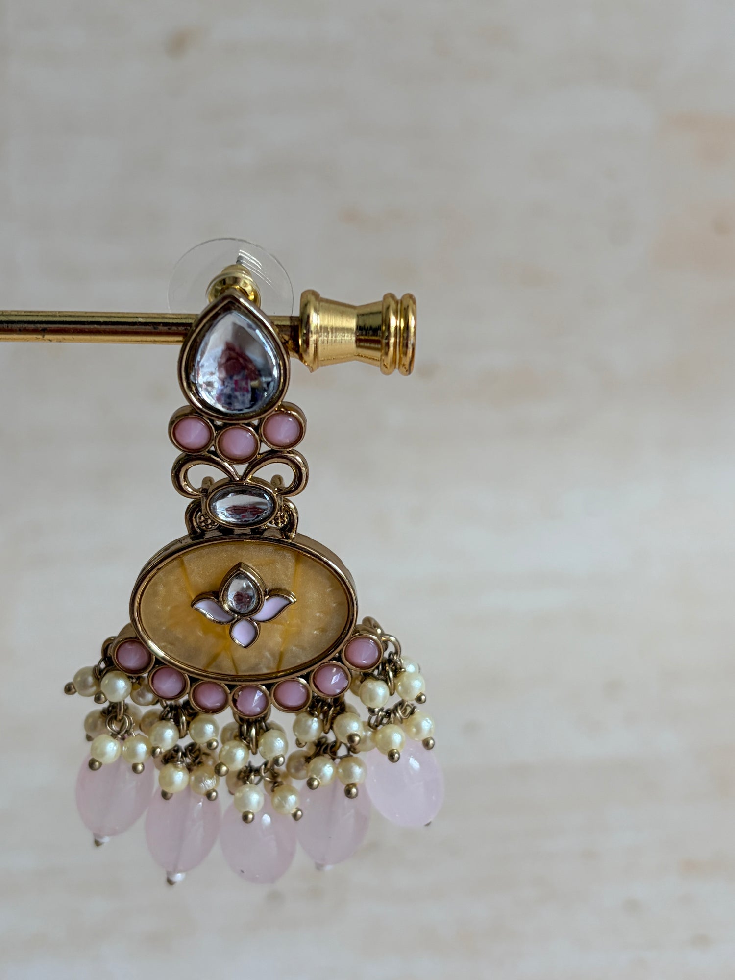Decorative brooch with gold, pink, and pearl details on a light background