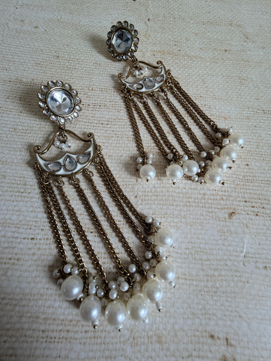 Vintage-style jewelry set with pearl-like beads and metallic chains on a textured beige background